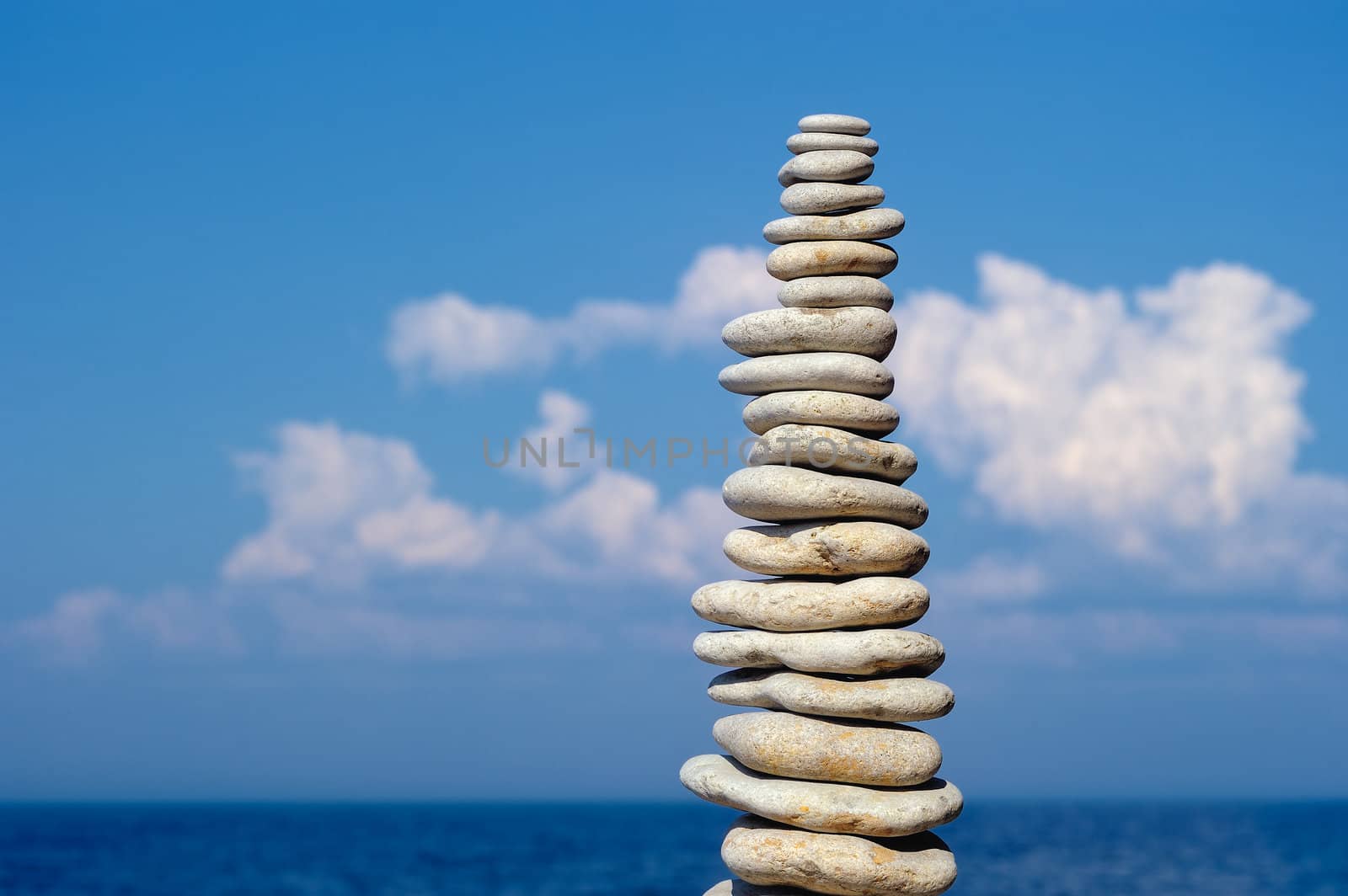 Balancing white pebbles each other on a sky background