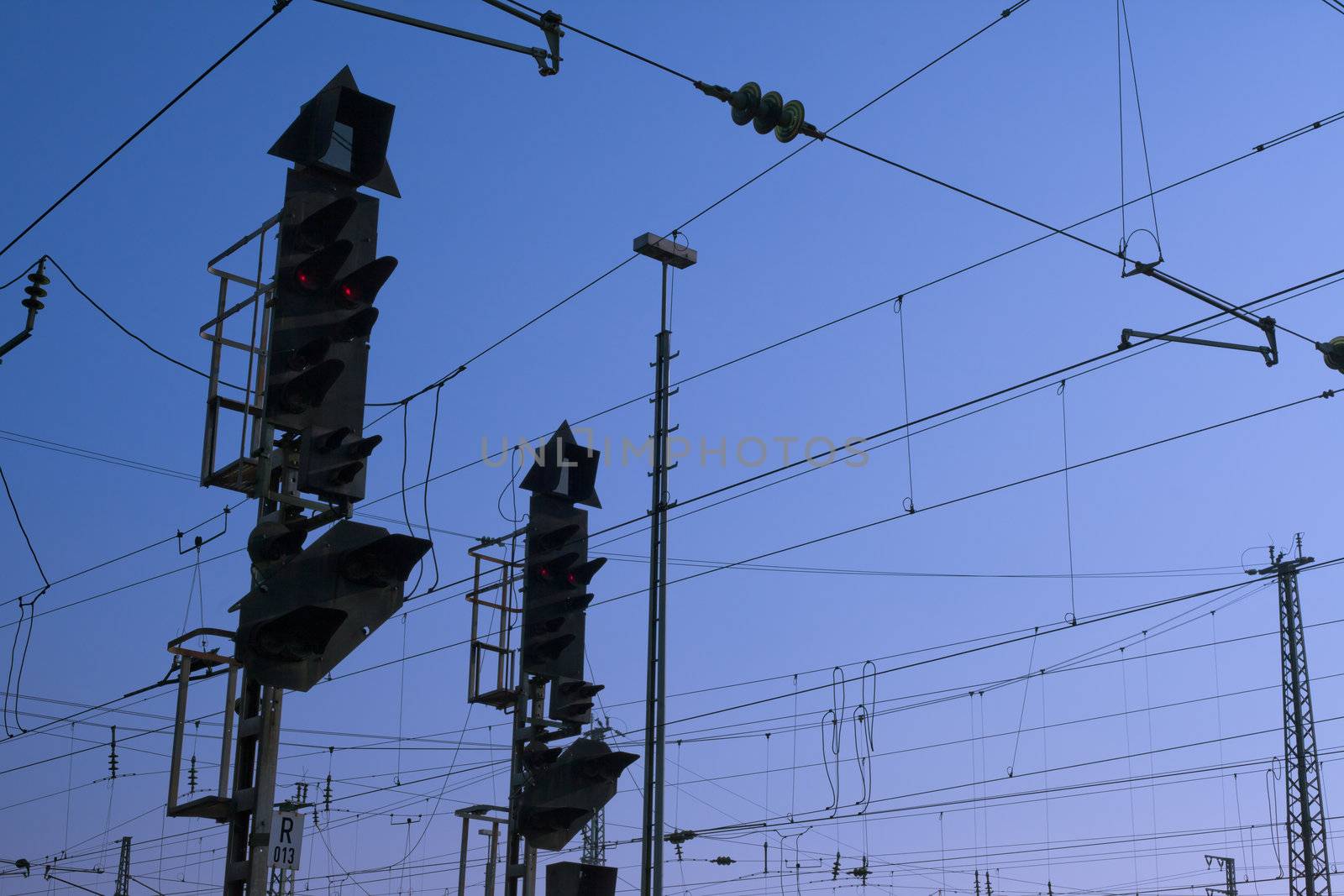 Red railway electric signal light and electric overhead contact wire all over.