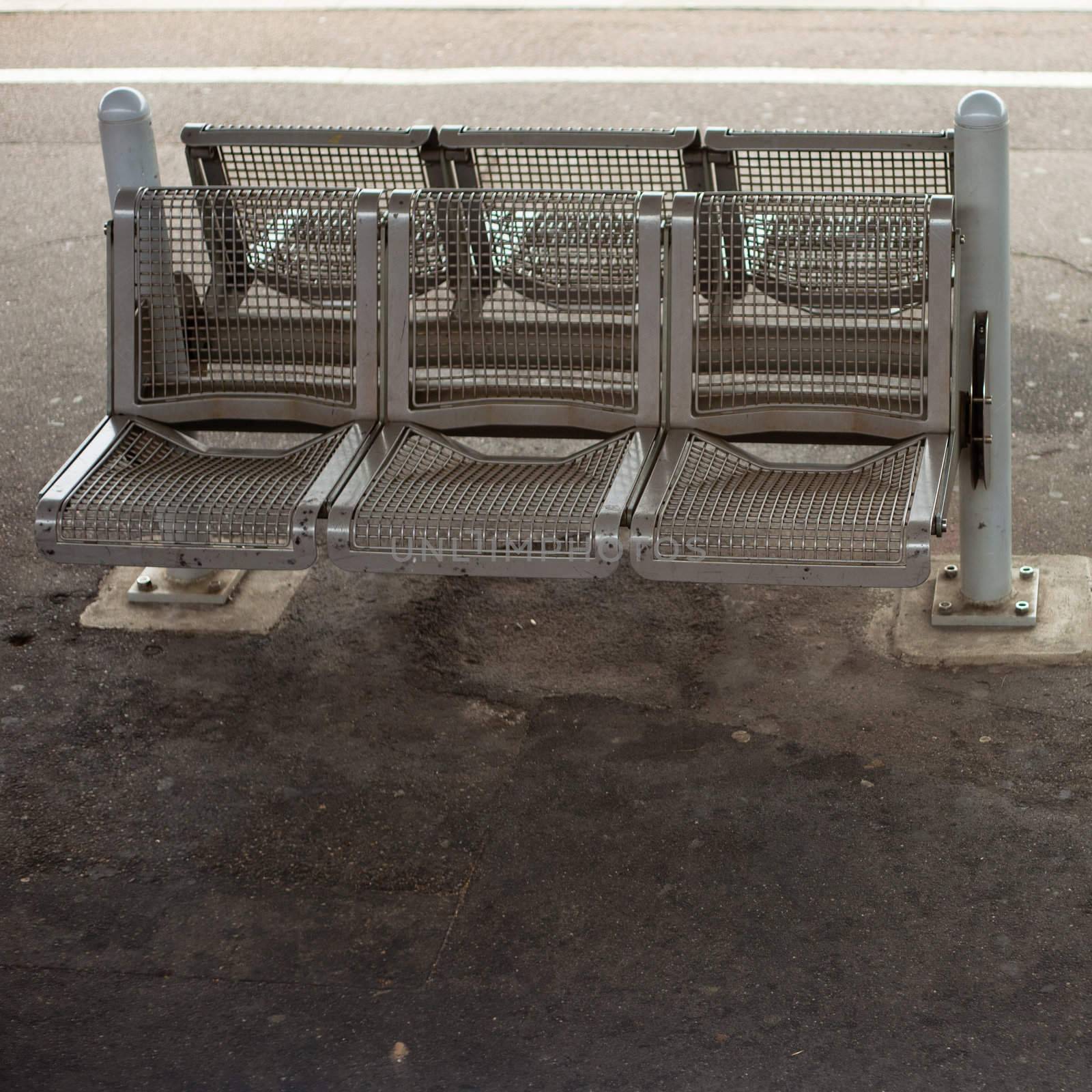 Empty steel bench bolted down on concrete platform.