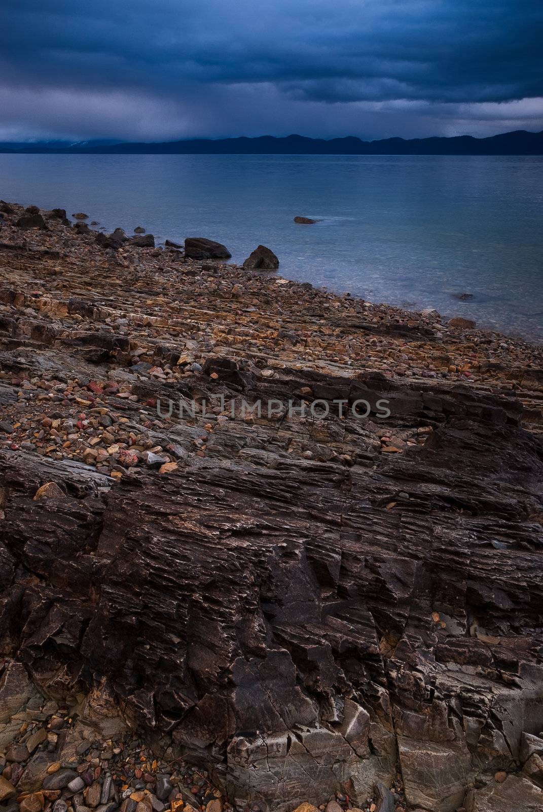 The rocky shore of Flathead Lake on a stormy evening in spring, West Shore State Park, Flathead County, Montana, USA by CharlesBolin