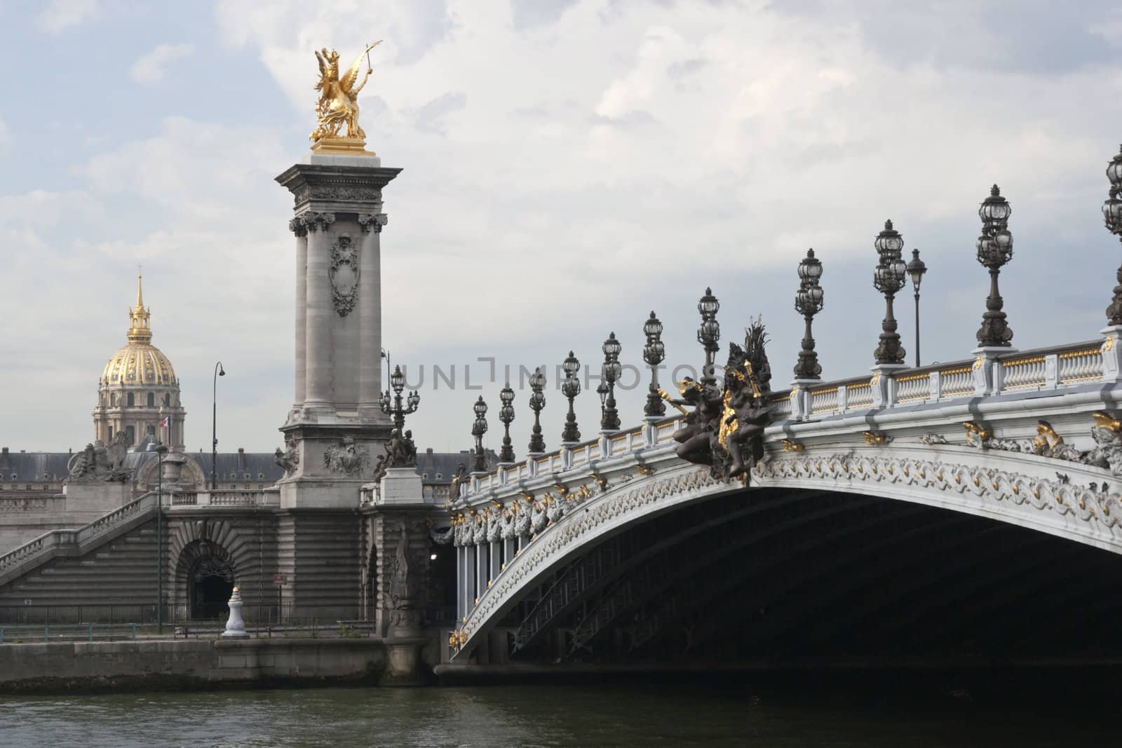 Historic bridge (Pont Alexandre III) over the River Seine in Paris, France. Gold of the Dome Church at Les Invalides in background.