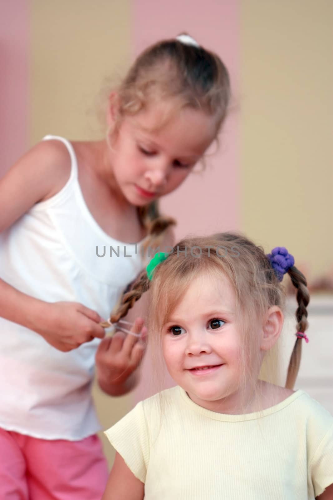Small girl getting hair comb by sister at home