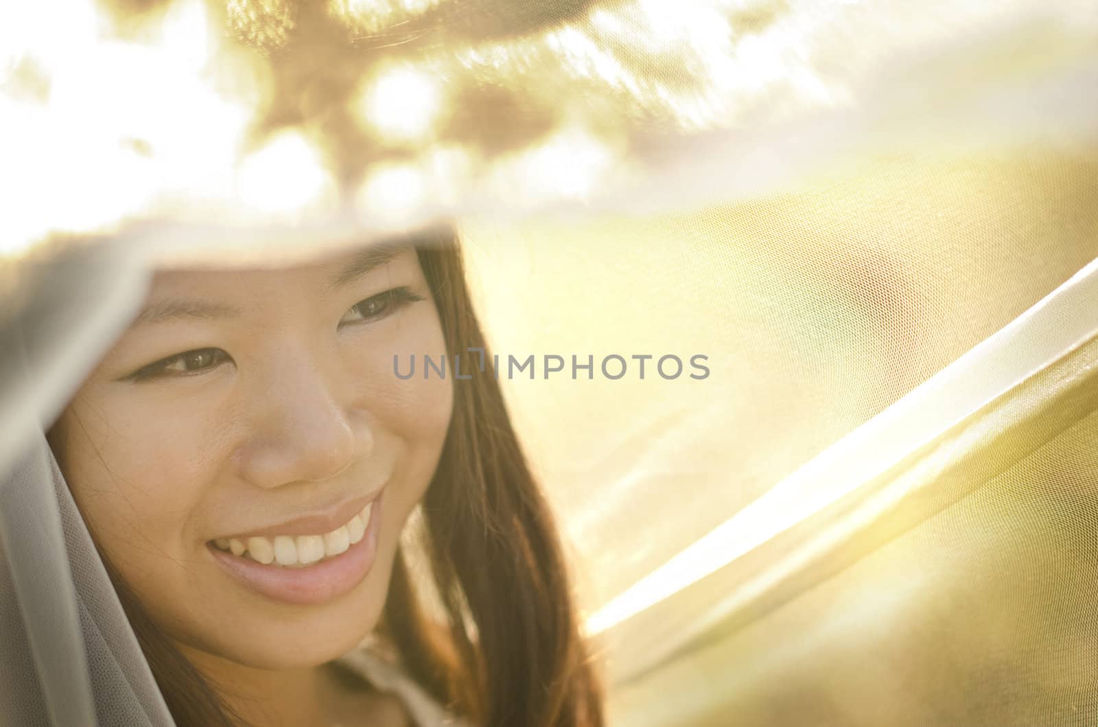 Asian bride under veil at outdoor in a morning surrounding by golden sunlight