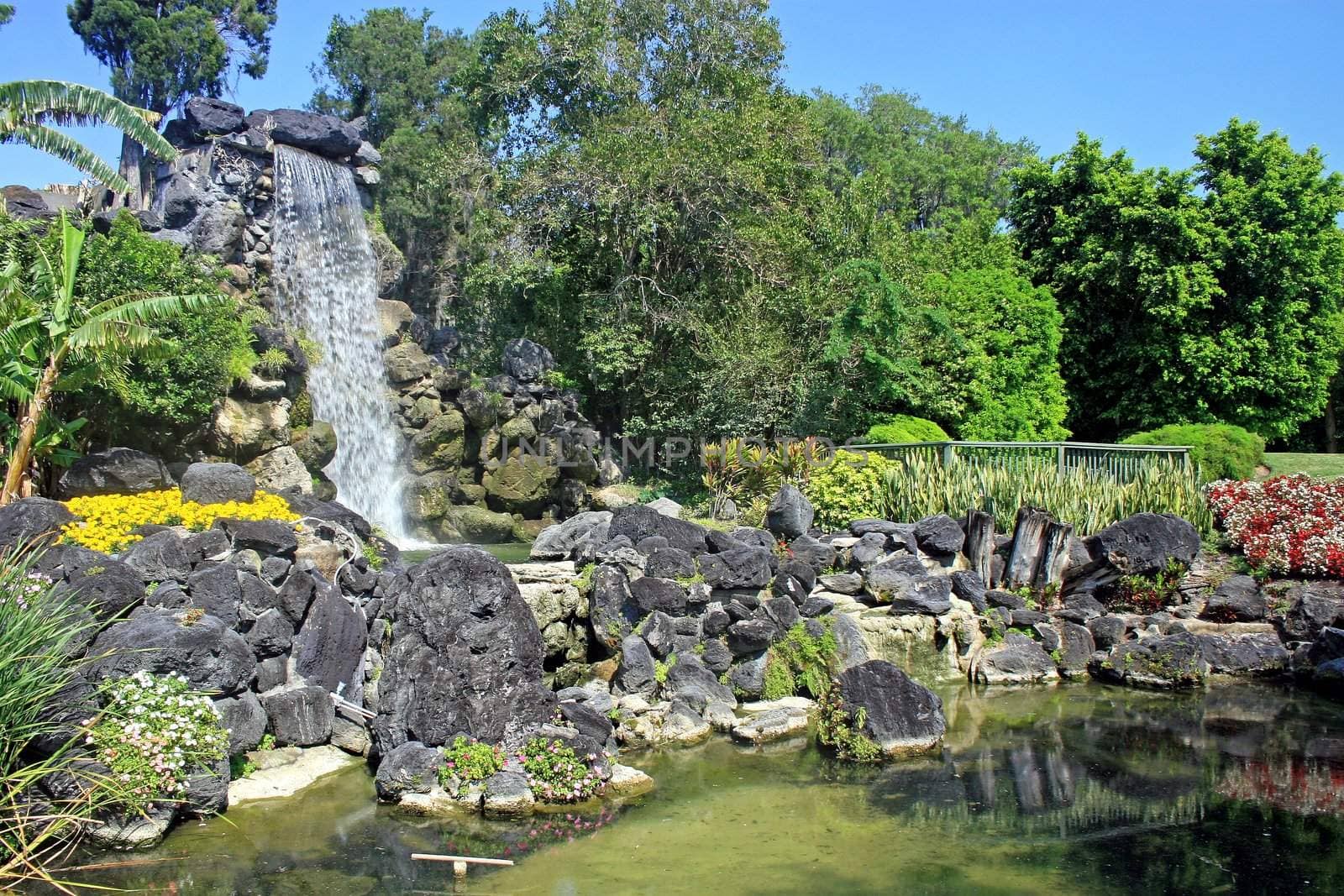 A waterfall and large rock feature in gardens