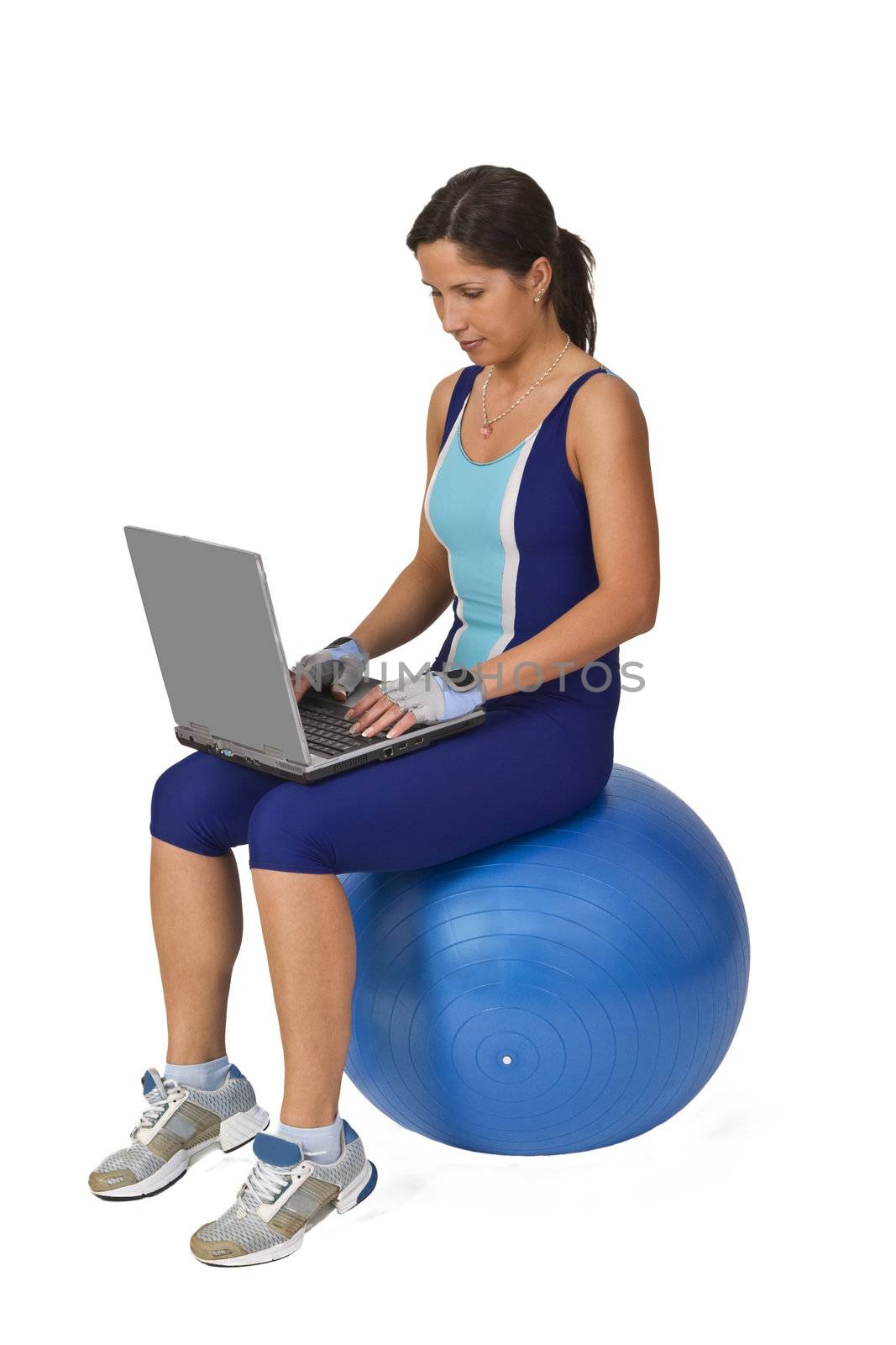 Woman in fitness equipment sitting on a gym ball and working on a laptop.Conceptual image to show the universality and mobility of technology and information.