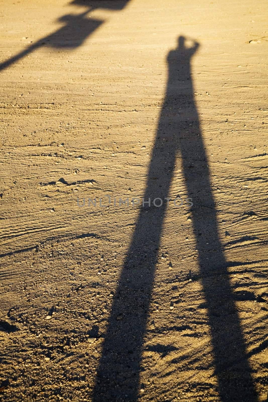 Shadow of man on dirt at sundown.