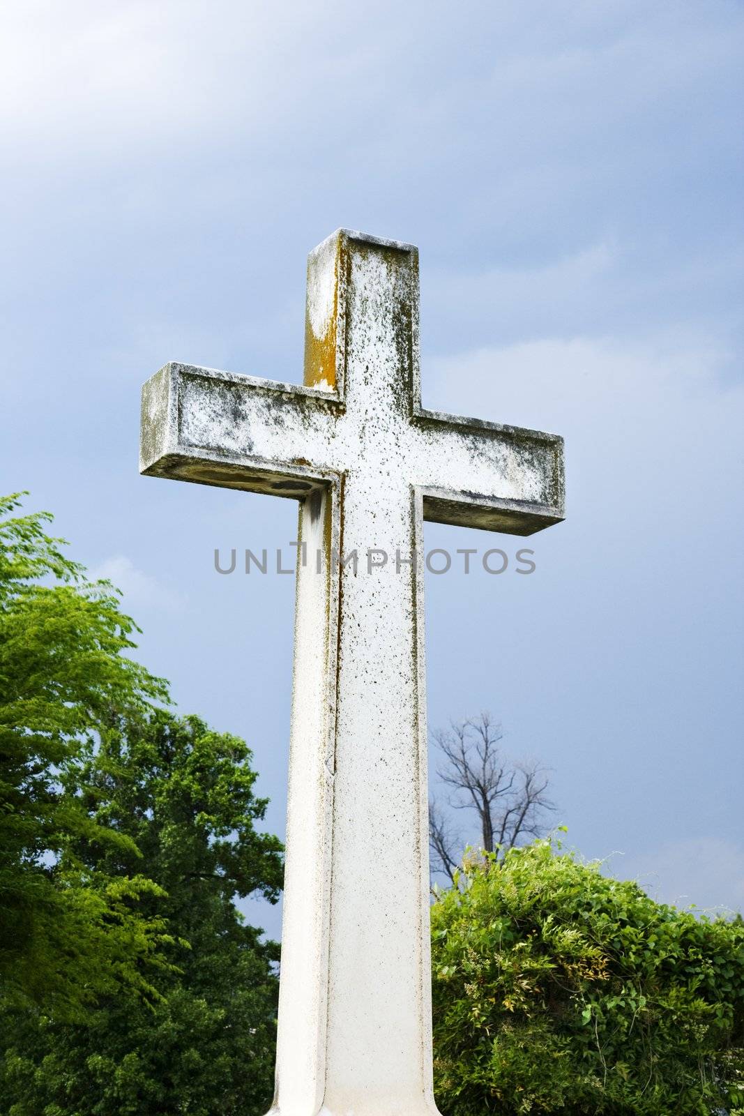 Cross in graveyard againstly blue sky and clouds