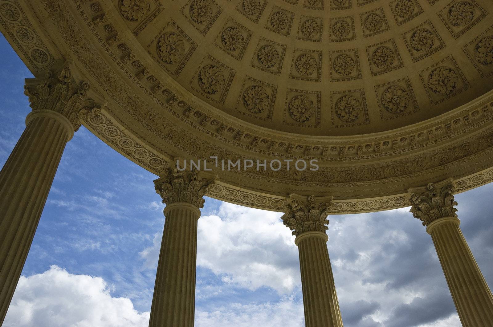 Wide-angle view from below showing details of the cupola of the Temple of Love in Marie-Antoniette's Estate in Versailles, Paris, France, including four Corinthian columns, sky and clouds