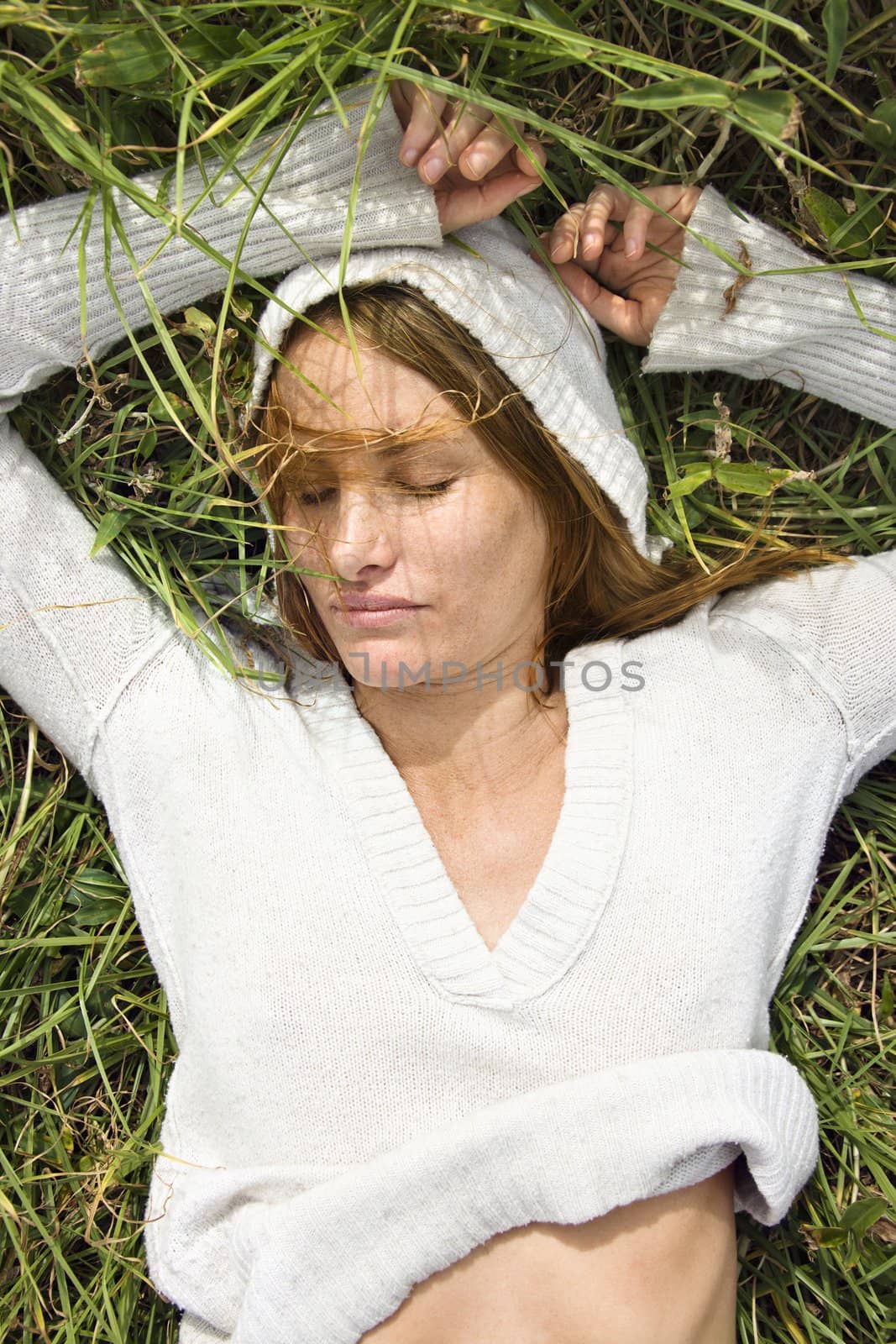 Portrait of attractive young redheaded woman lying in grass resting.