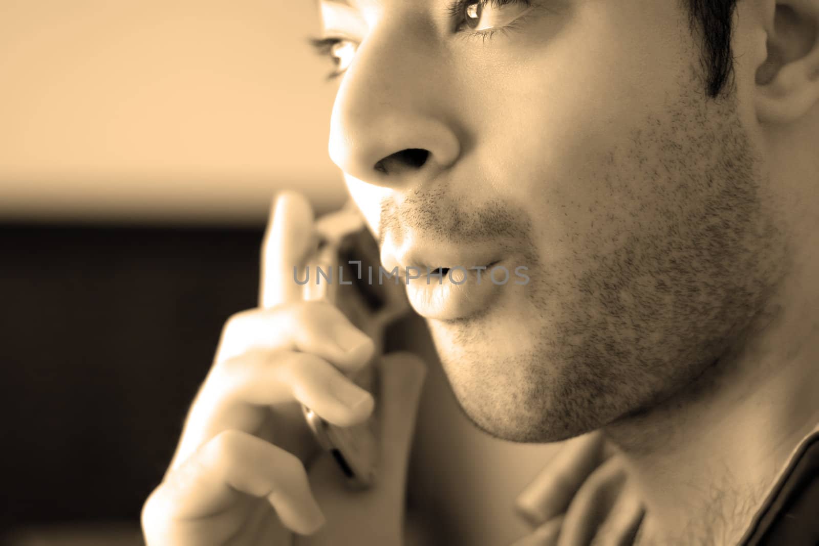 Sepia toned portrait of a young man on his celly phone - he looks surprised from what he has just heard.