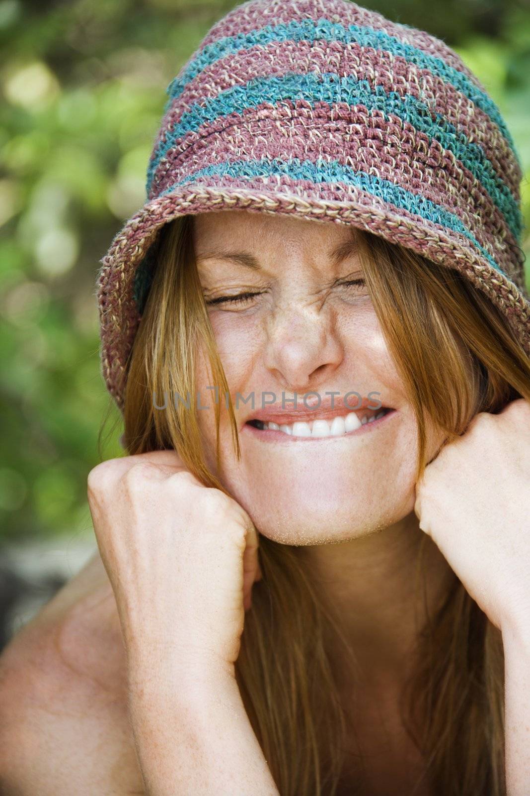 Portrait of pretty redhead with goofy expression on her face wearing hat.