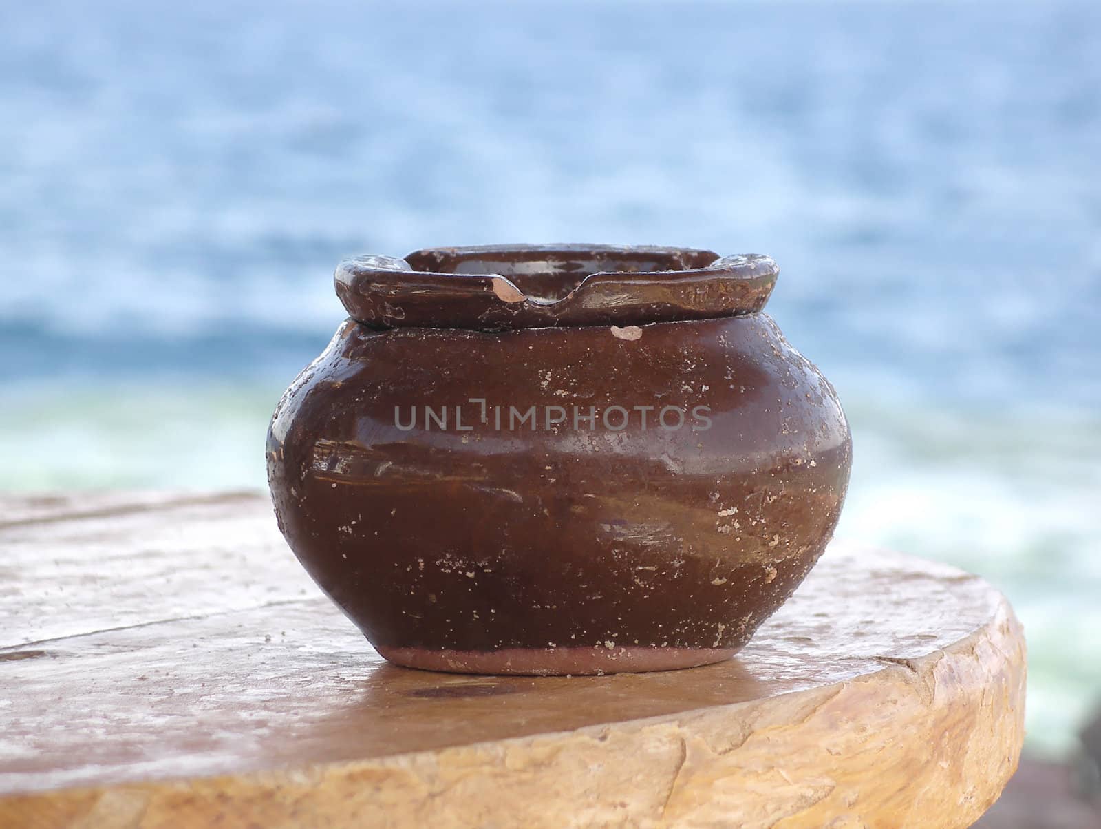Close view of a ceramical vase on a table in front of the ocean