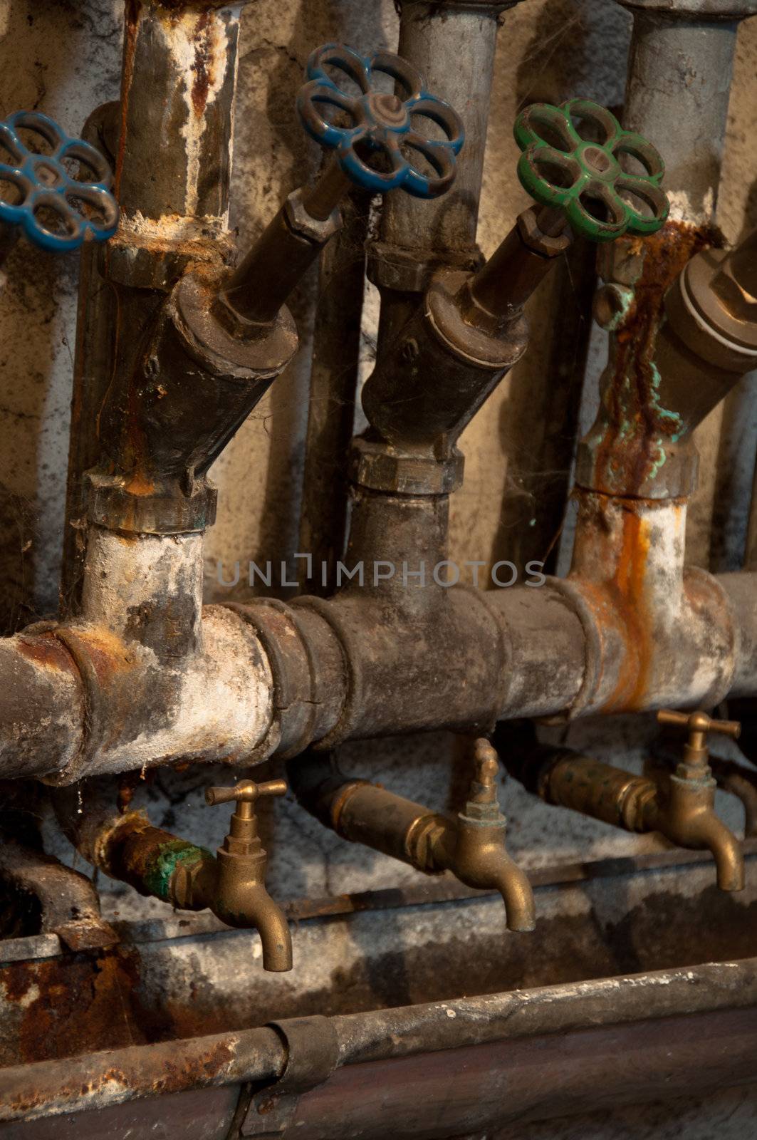 Old rusty pipes and valves in cellar of old house