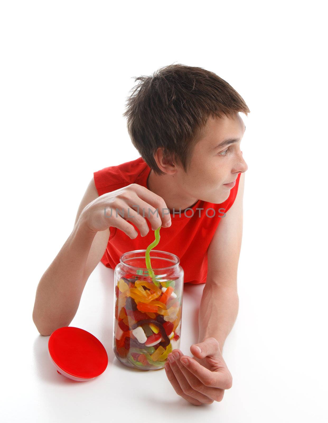 A young boy pulling a long green snake from a lolly jar.  He is looking sideways.  Space for copy.  White background.