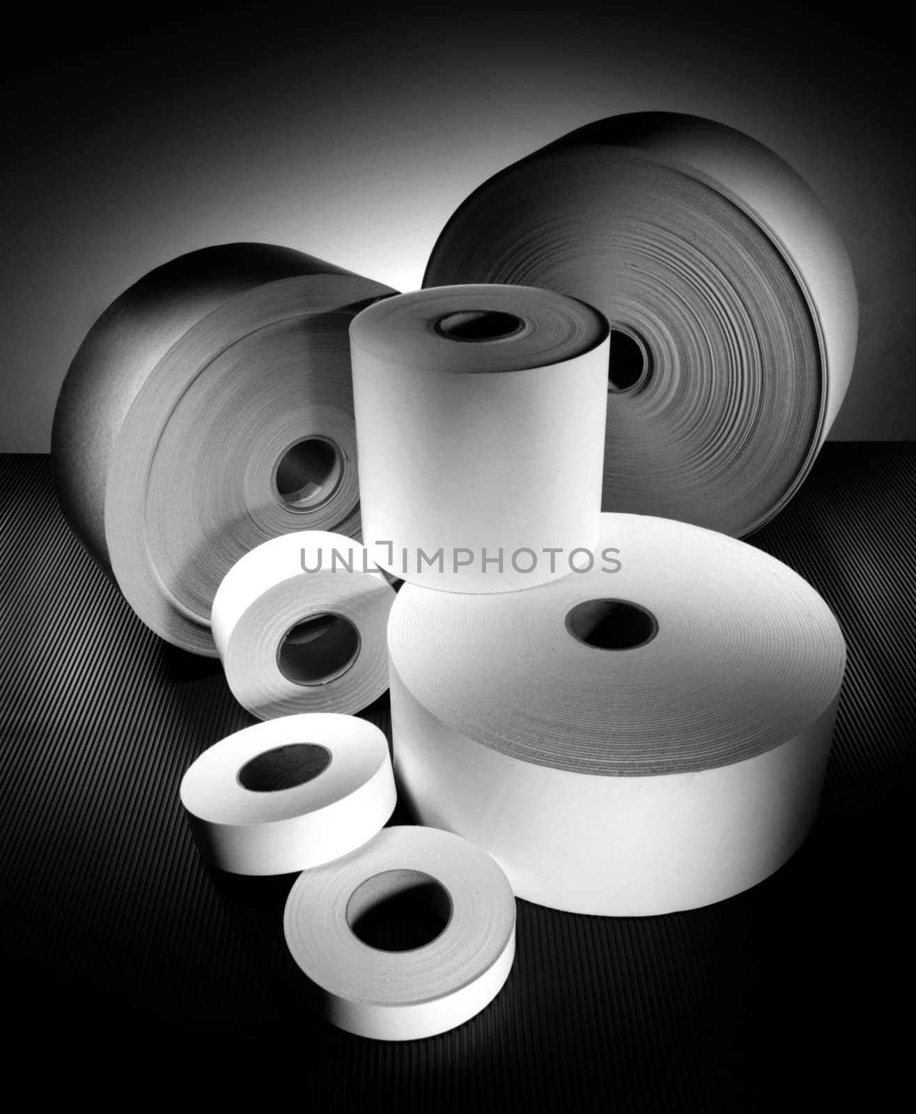 rolls of different sized paper on dark background in black and white