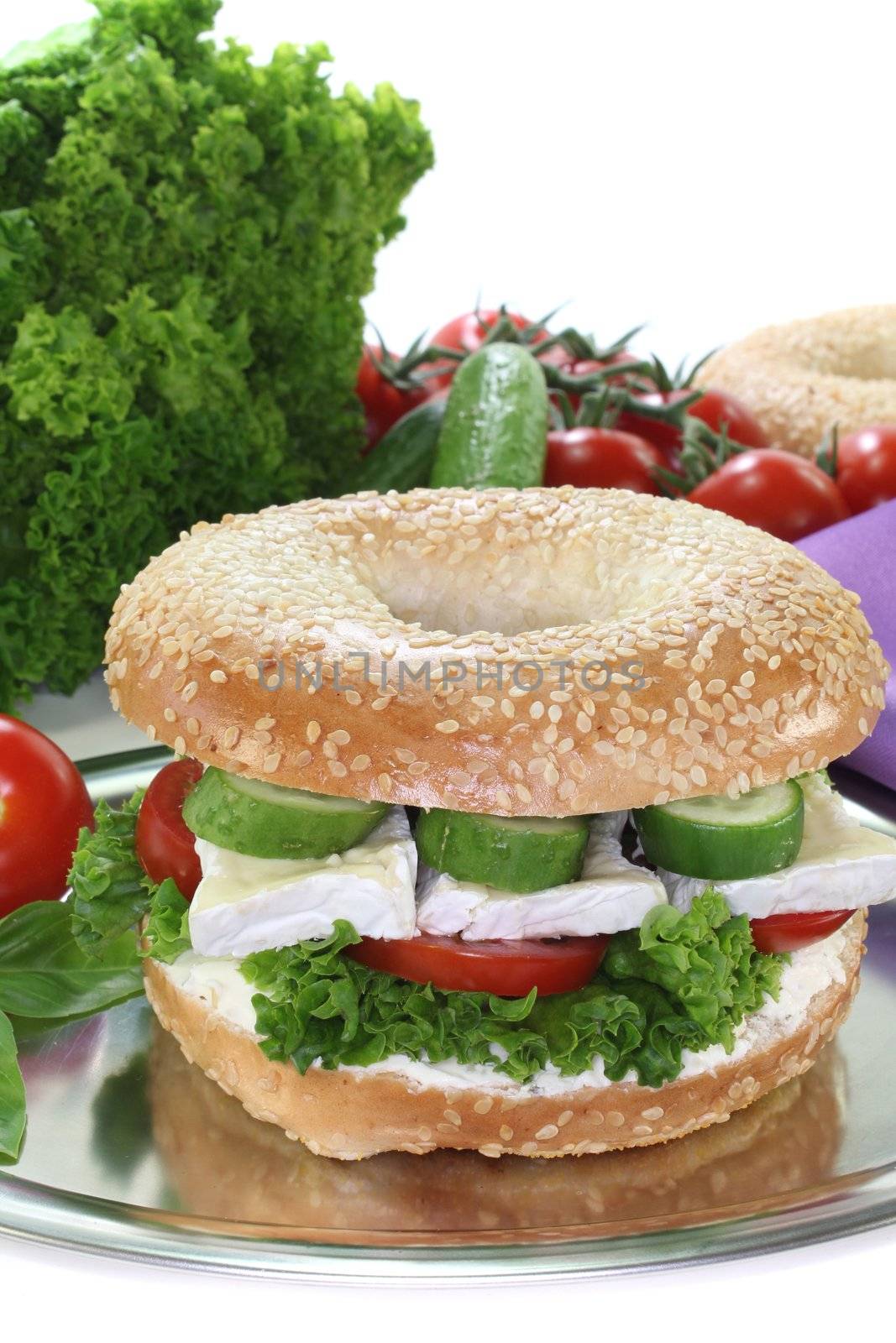 Bagel with Camembert cheese, tomato, cucumber, cream cheese and lettuce on white background