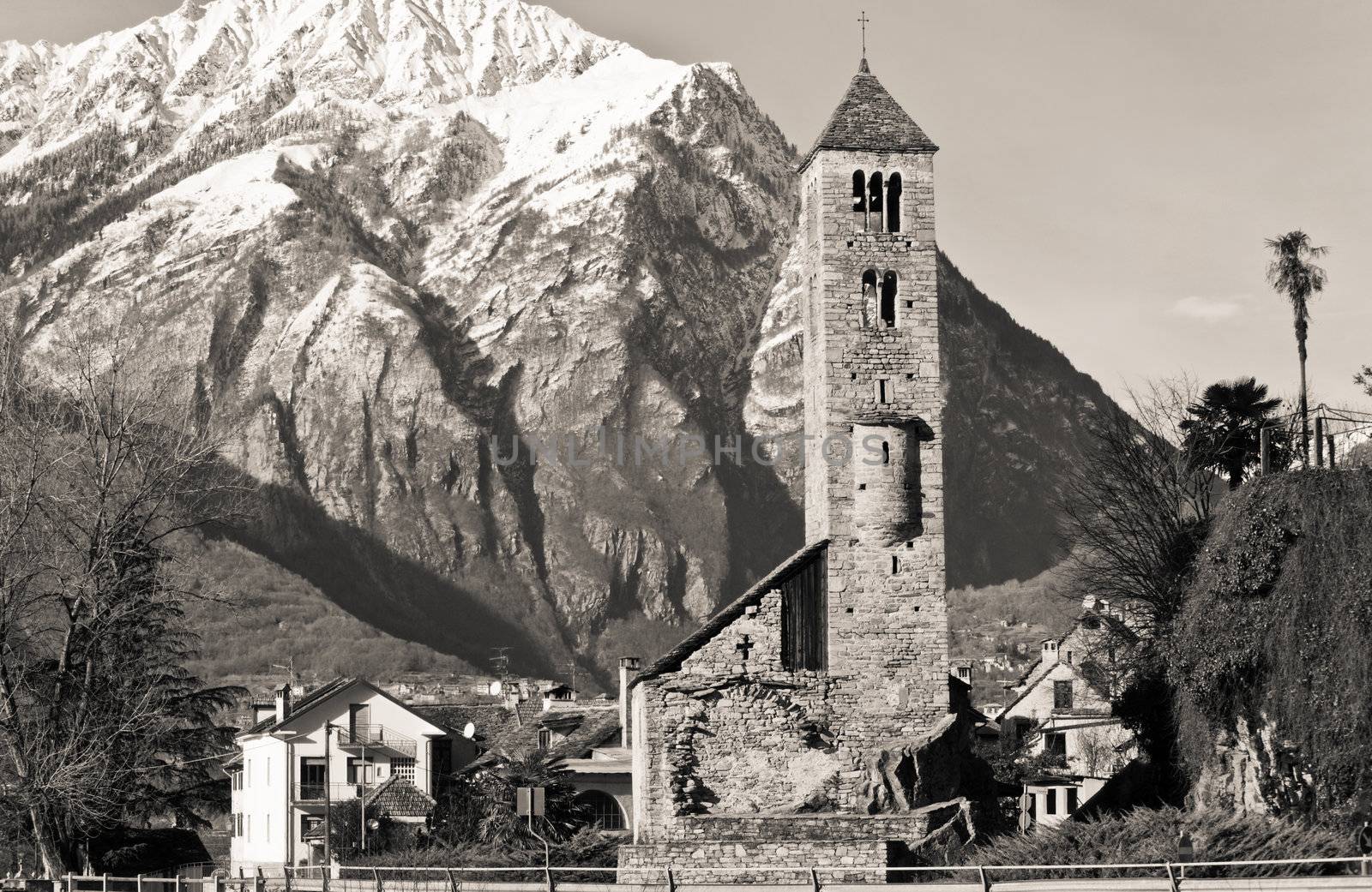Sepia toned shot of an ancient Italian church with the Alps in the background