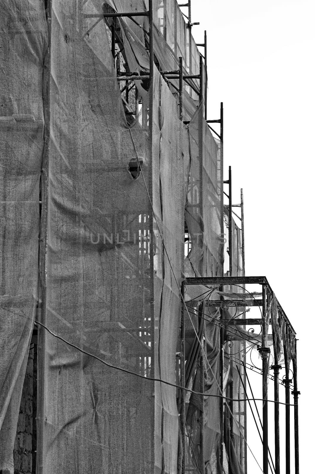 Abandoned mansion covered with torn debris netting. Black and white.