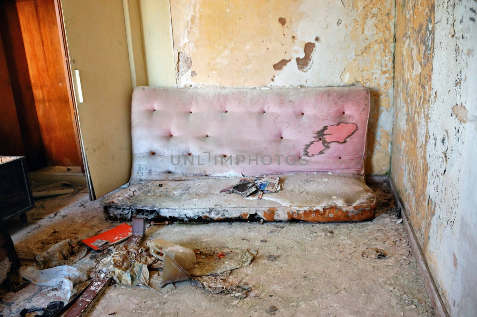 Broken couch and peeling paint wall. Abandoned house interior.