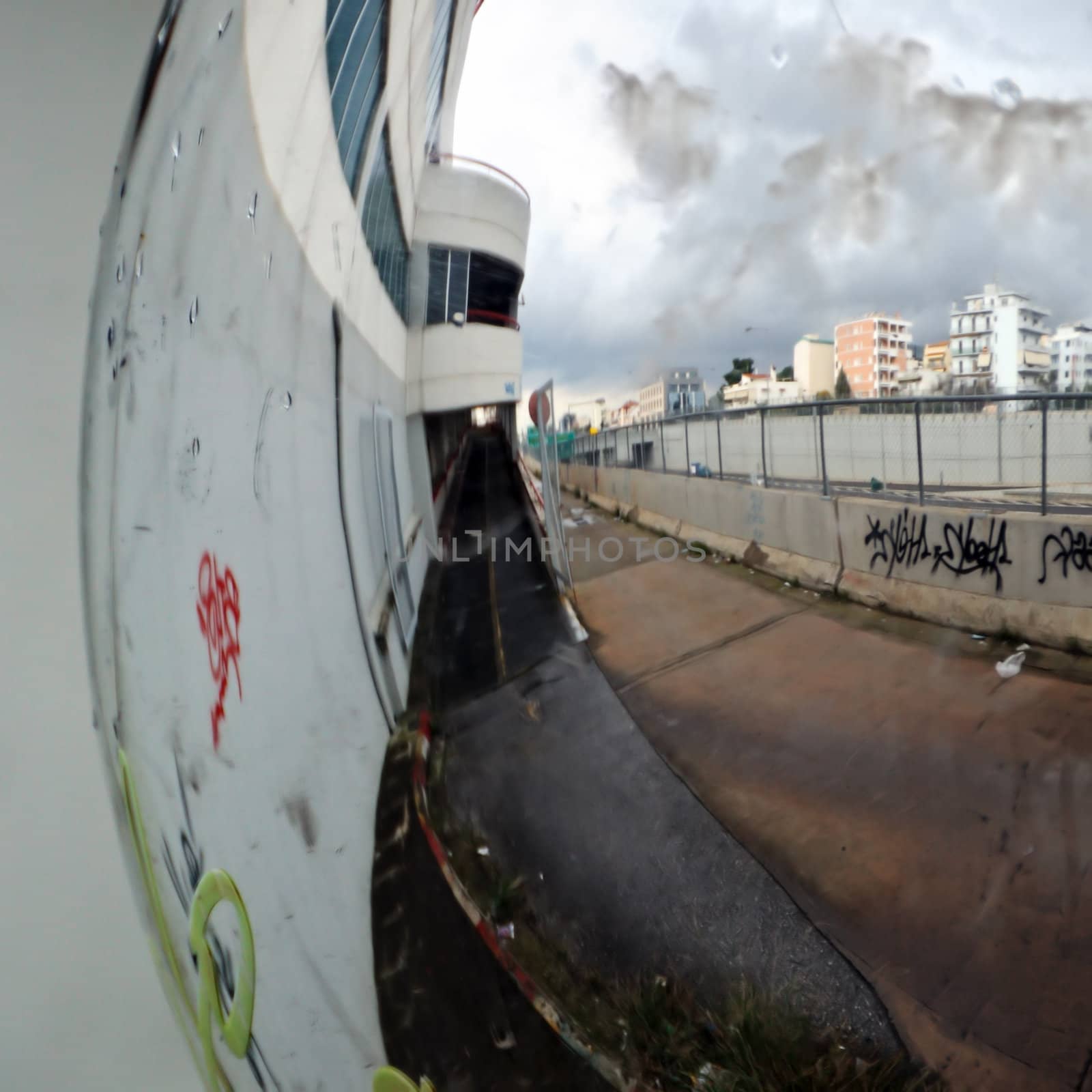 Distorted view of cityscape in the rain mirrored on convex parking mirror.