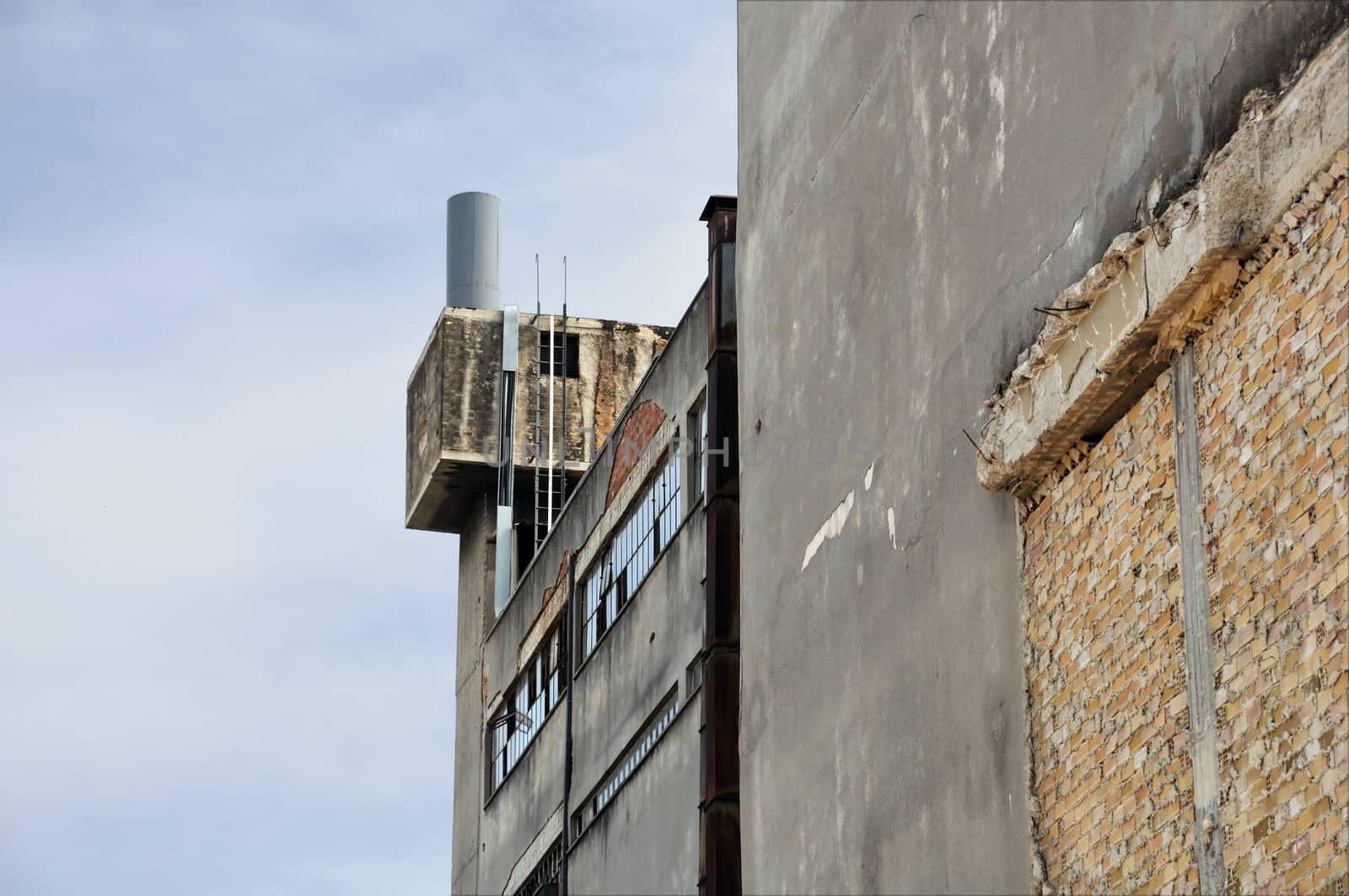 Abandoned factory exterior and crumbling wall. Industrial building.