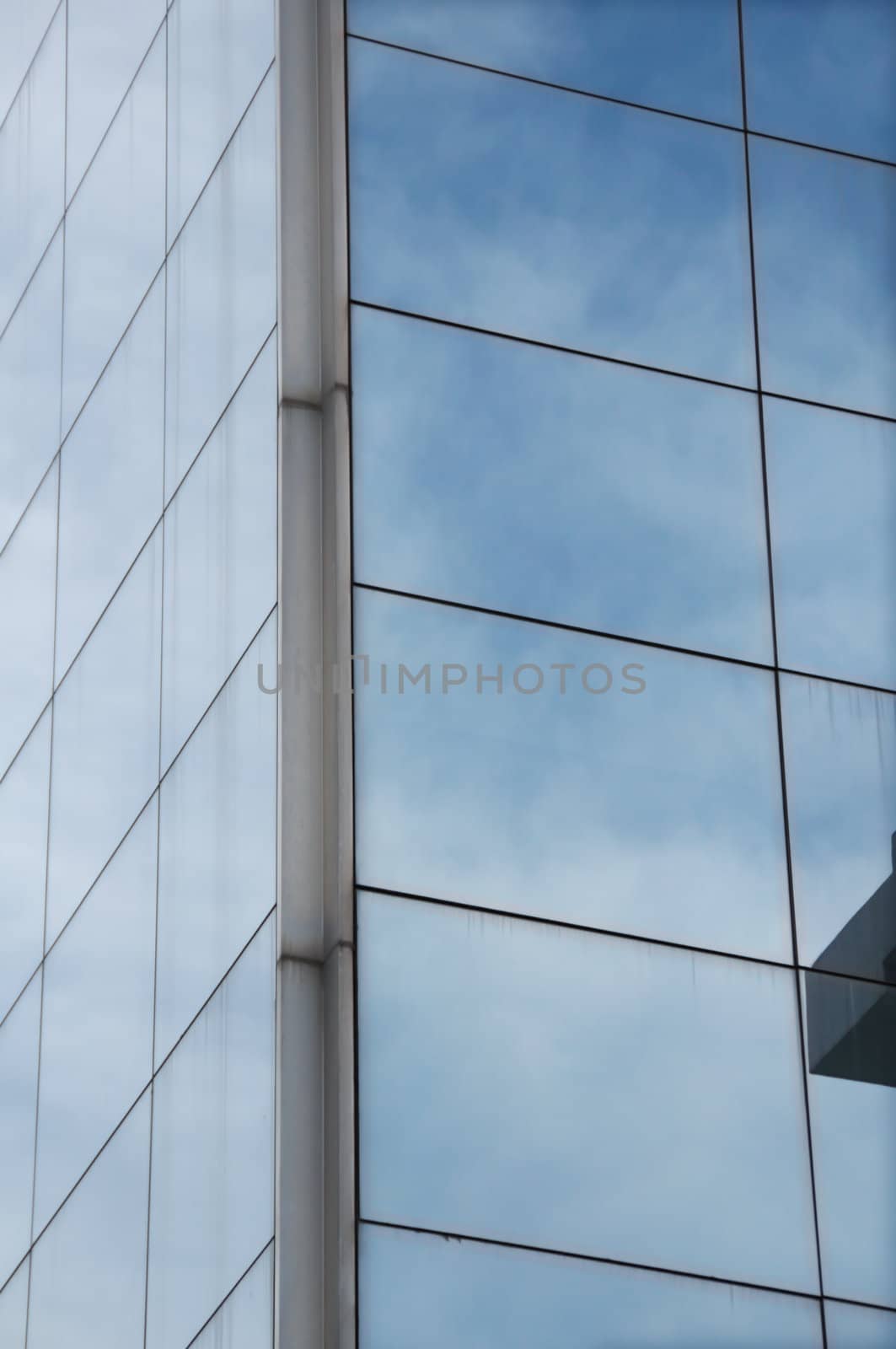 Sky mirrored on the windows of a modern glass building. Architectural detail.