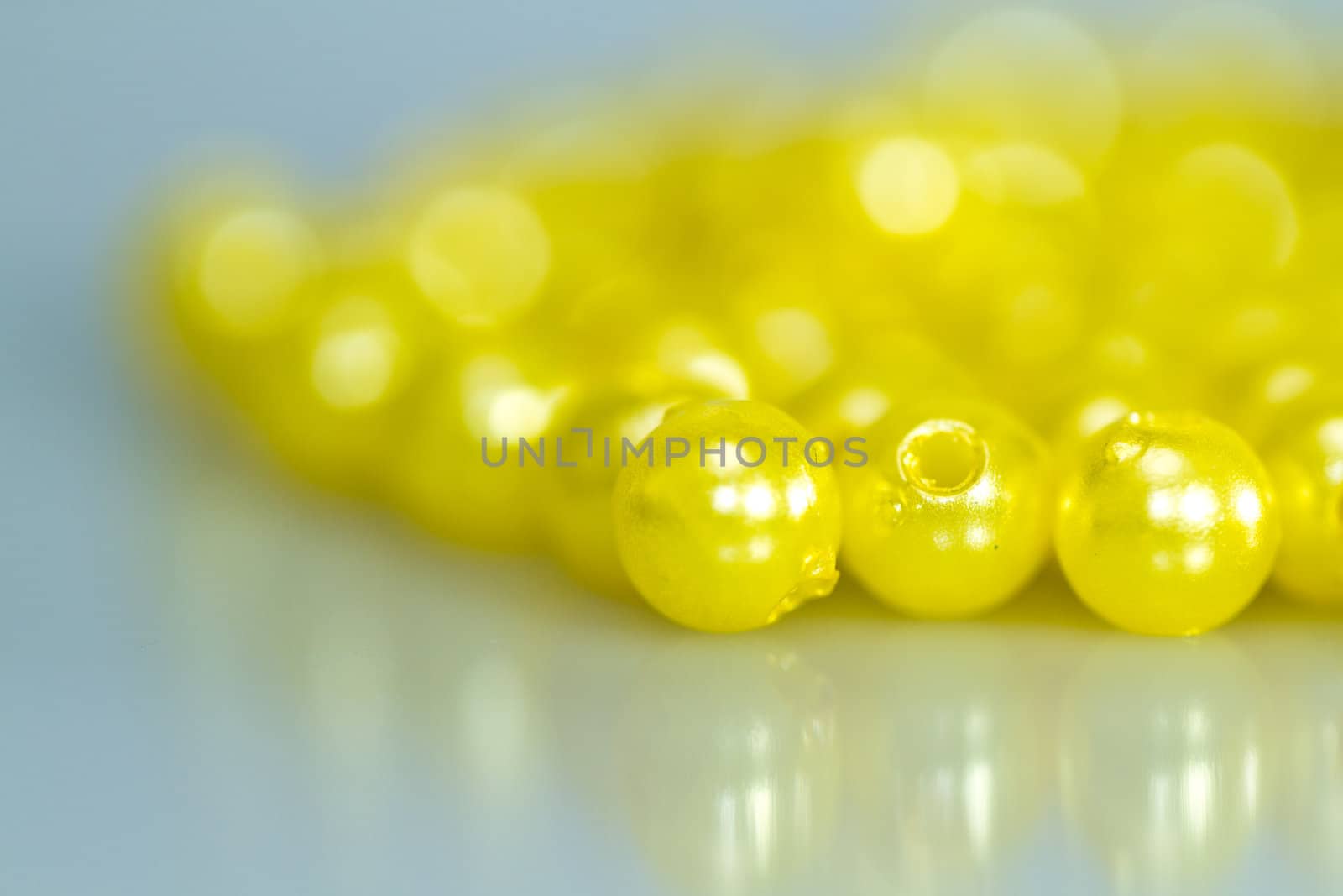 Yellow beads on bluish surface with mirror image