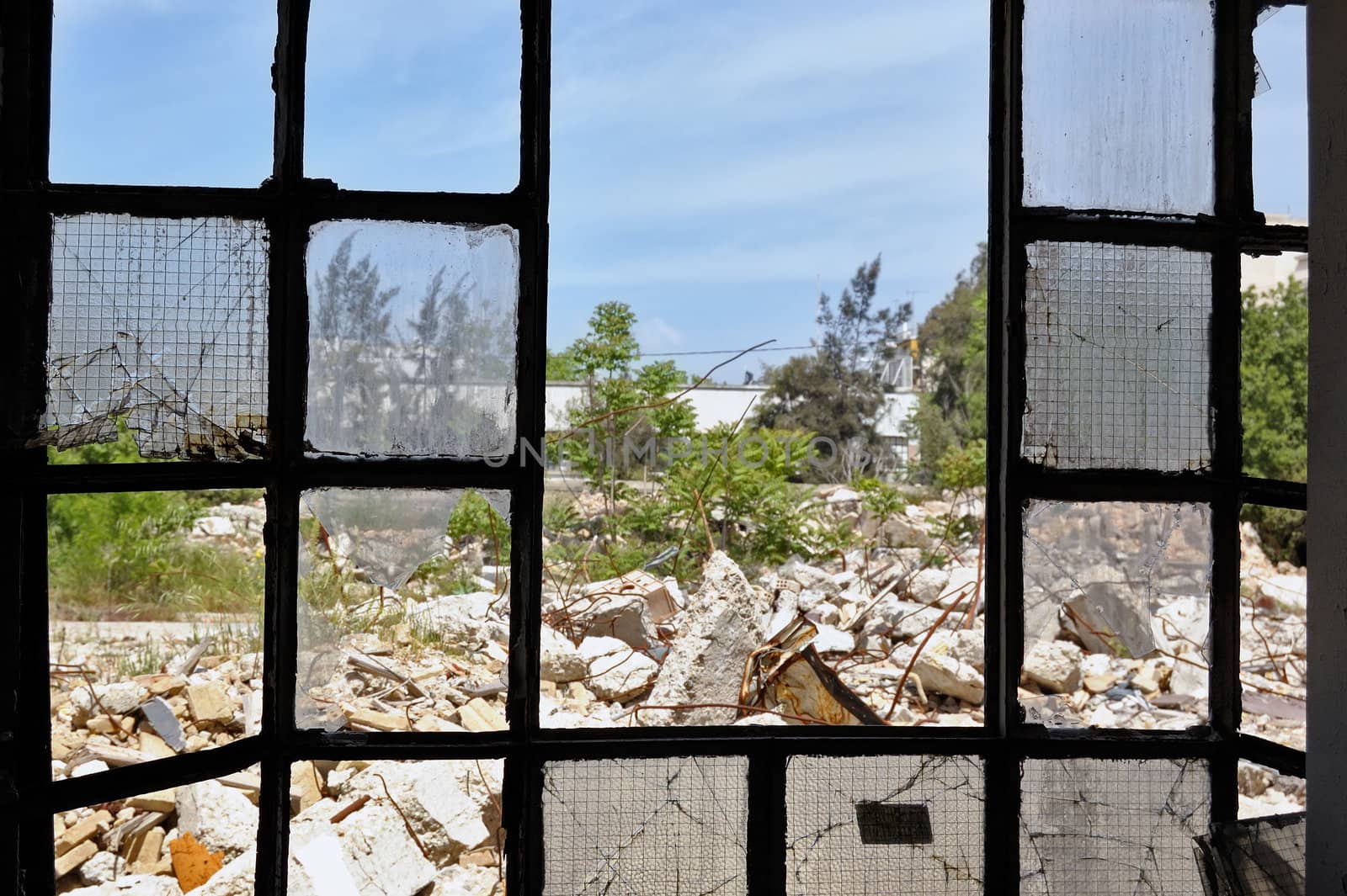 View to a pile of rubble from the broken windows of a partially demolished factory.