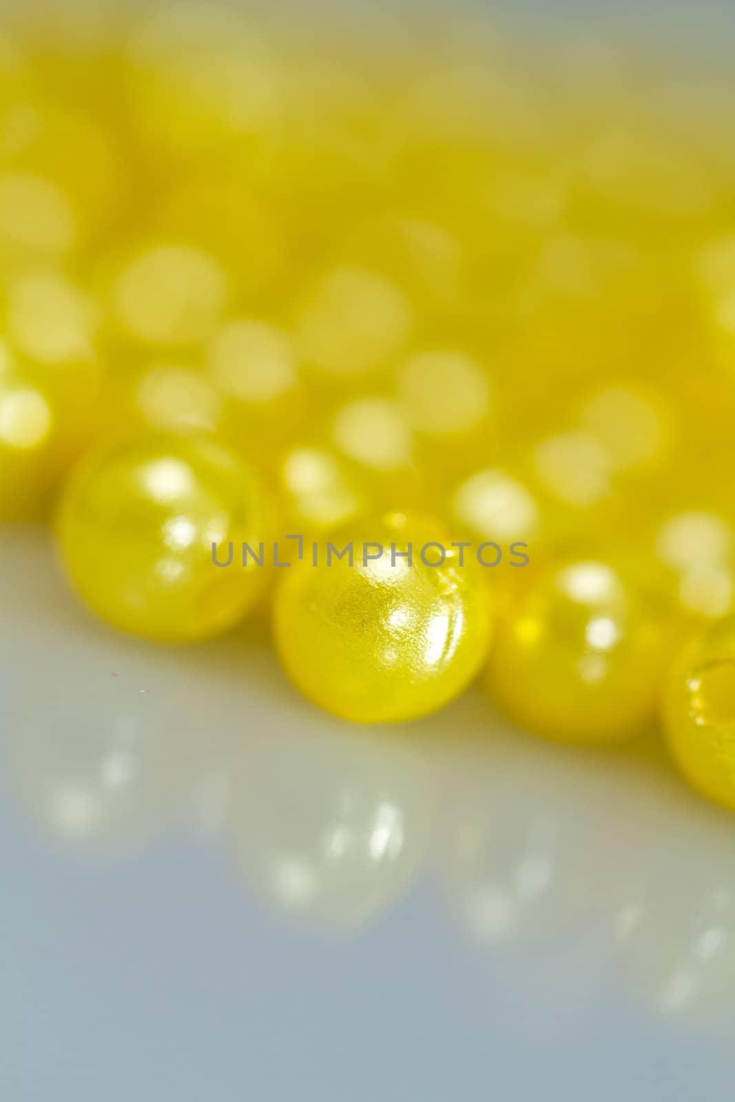 Yellow beads on bluish surface with mirror image in portrait orientation