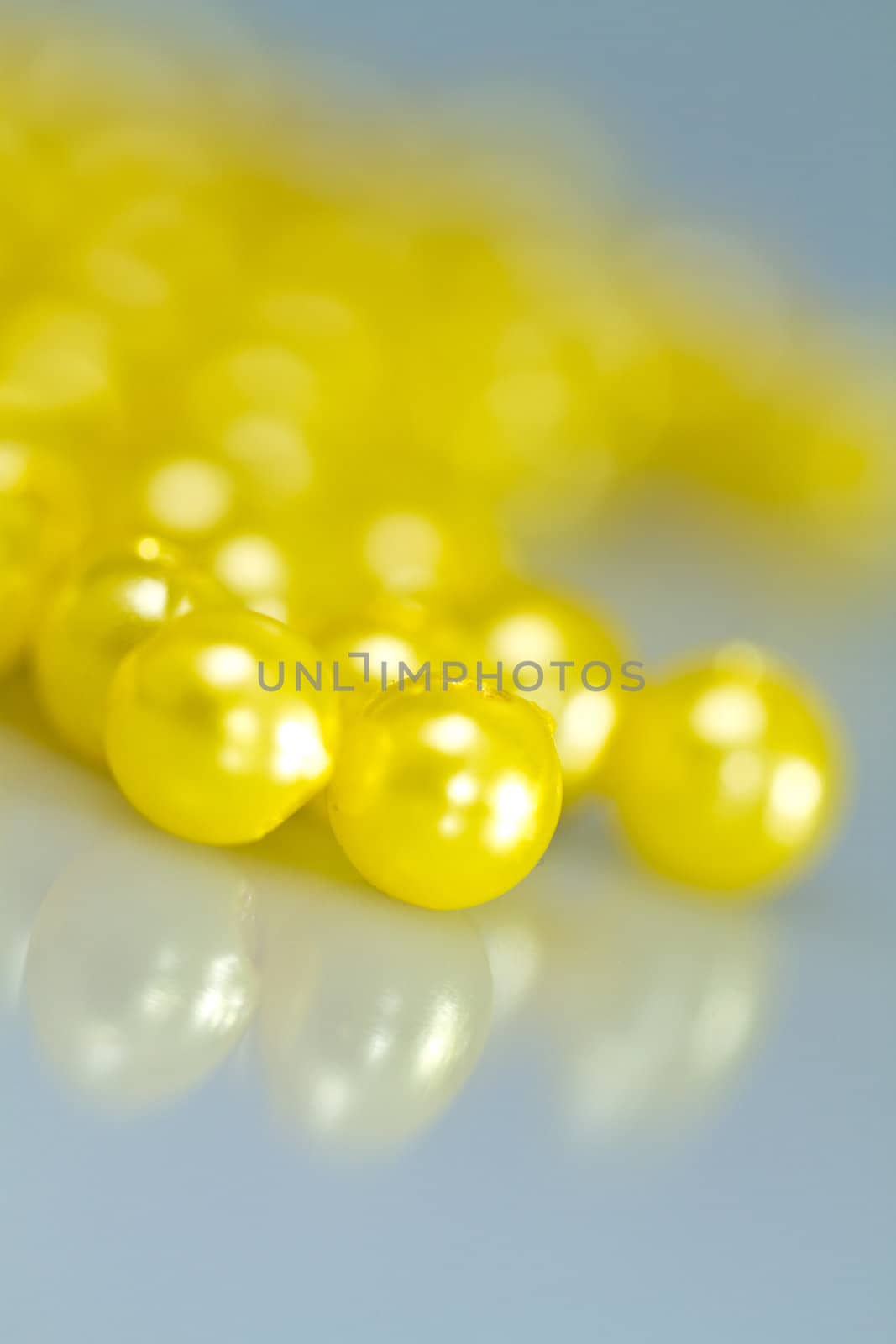 Yellow beads on bluish surface with mirror image in portrait orientation