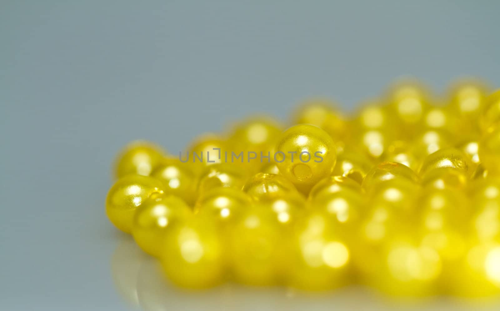 Yellow beads on bluish surface with mirror image