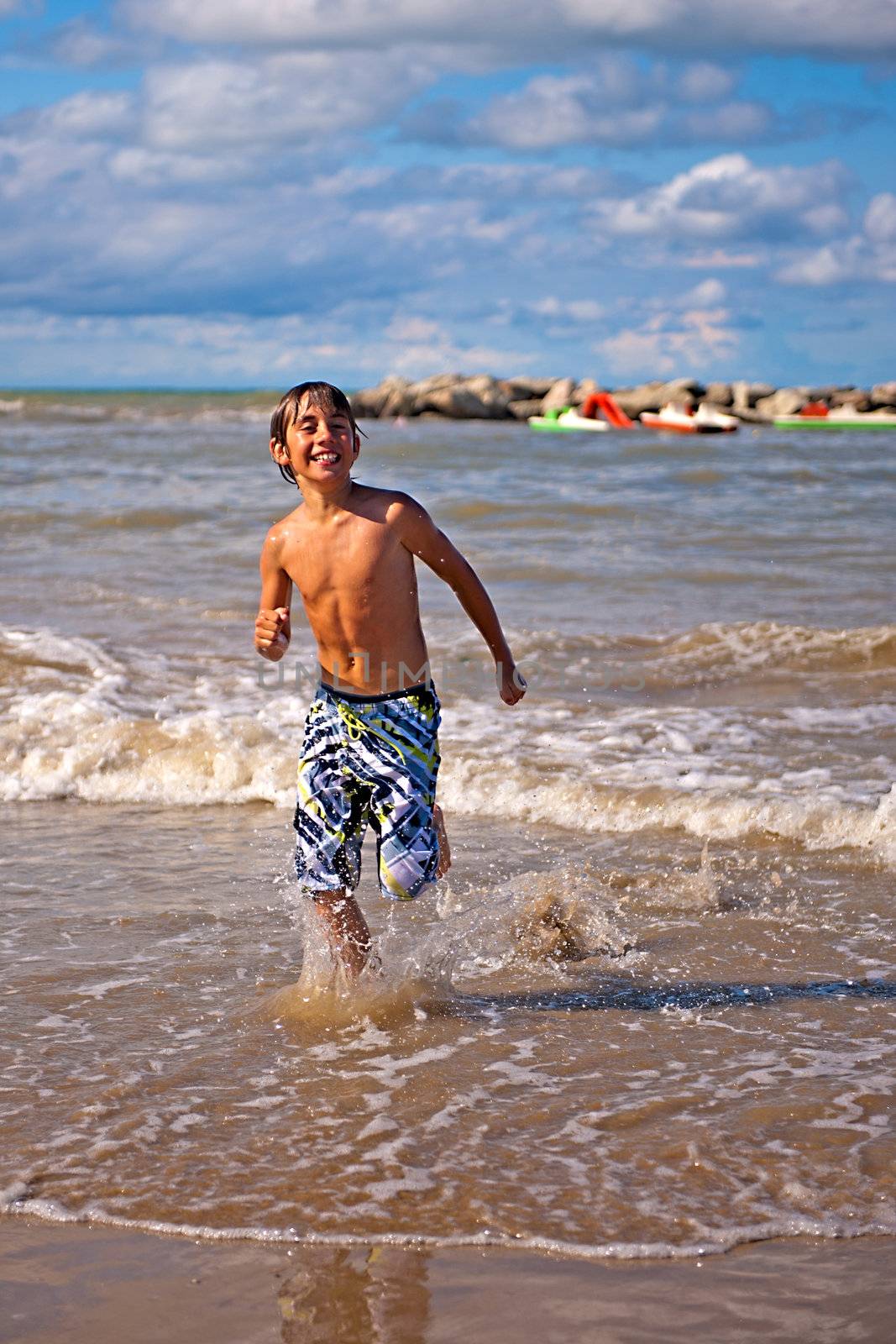 a boy is running on the beach on a sunny day