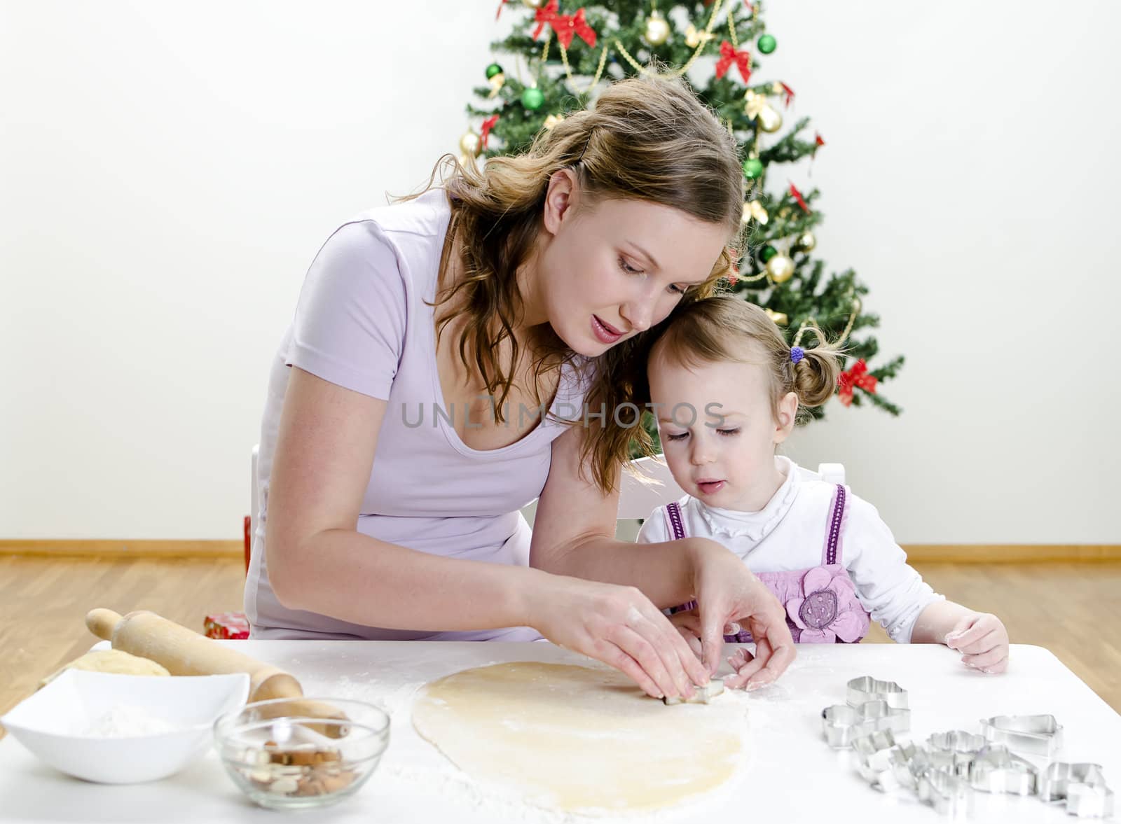 little girl and mother are preparing Christmas cookies