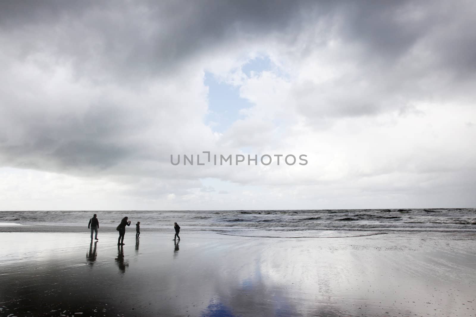 family of four having fun at the beach on a cloudy day