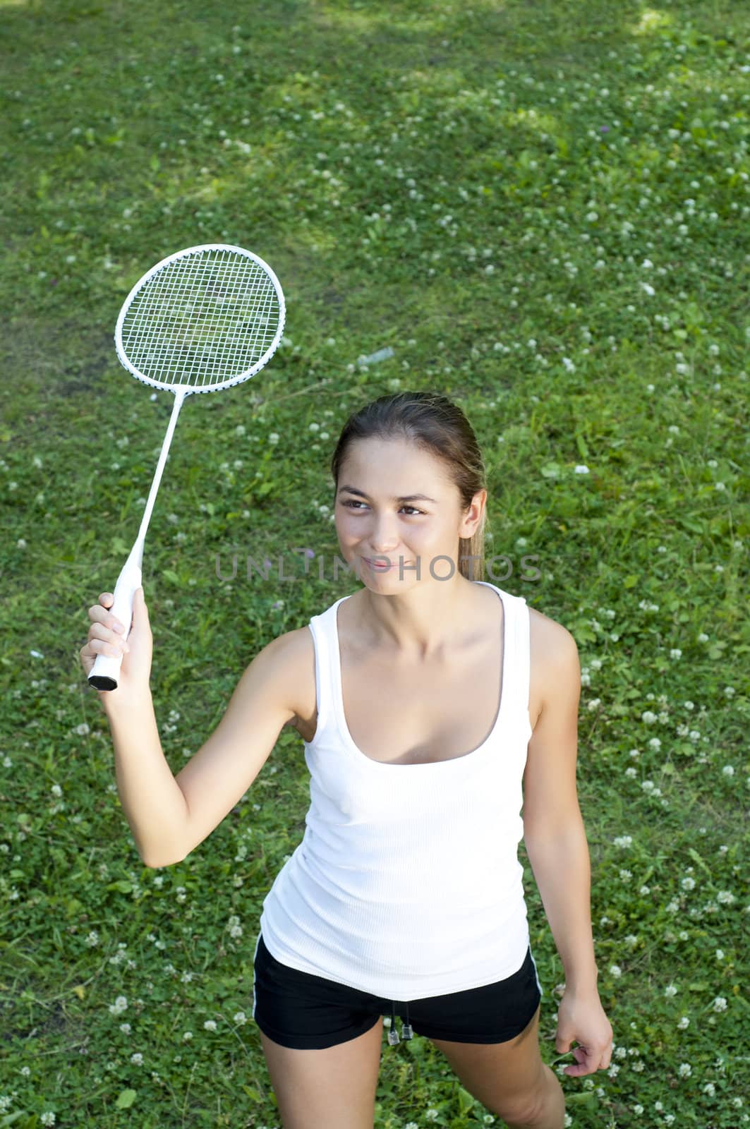 Beautiful Young Woman Playing Badminton, green grass background
