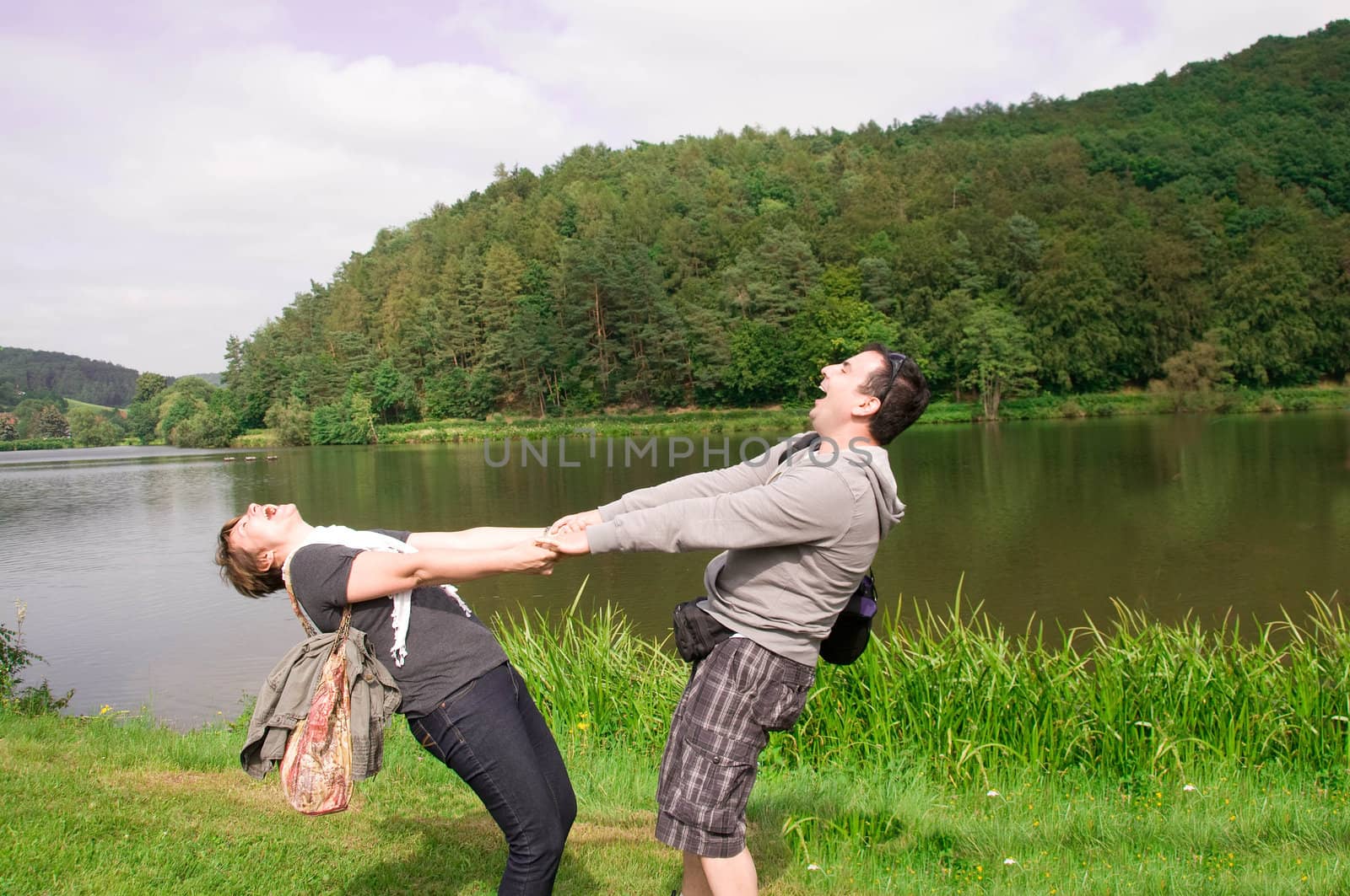 Young man and woman holding hands, spinning and laughing.