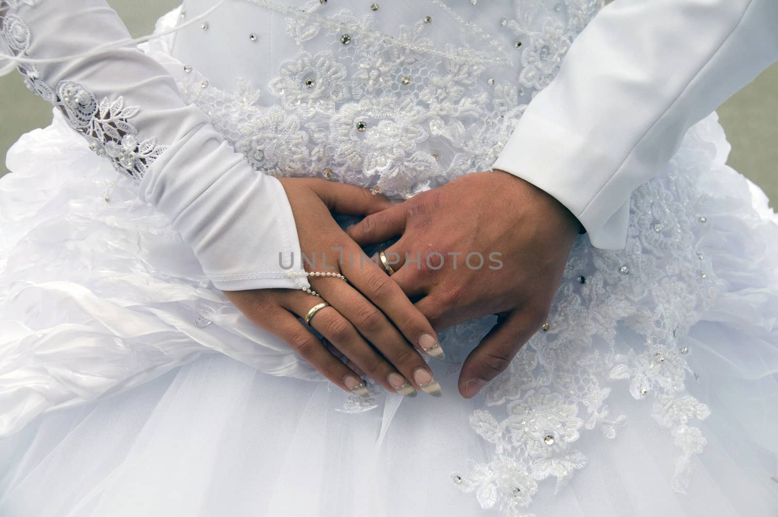Hands of newlyweds on the background of the bride dresses.