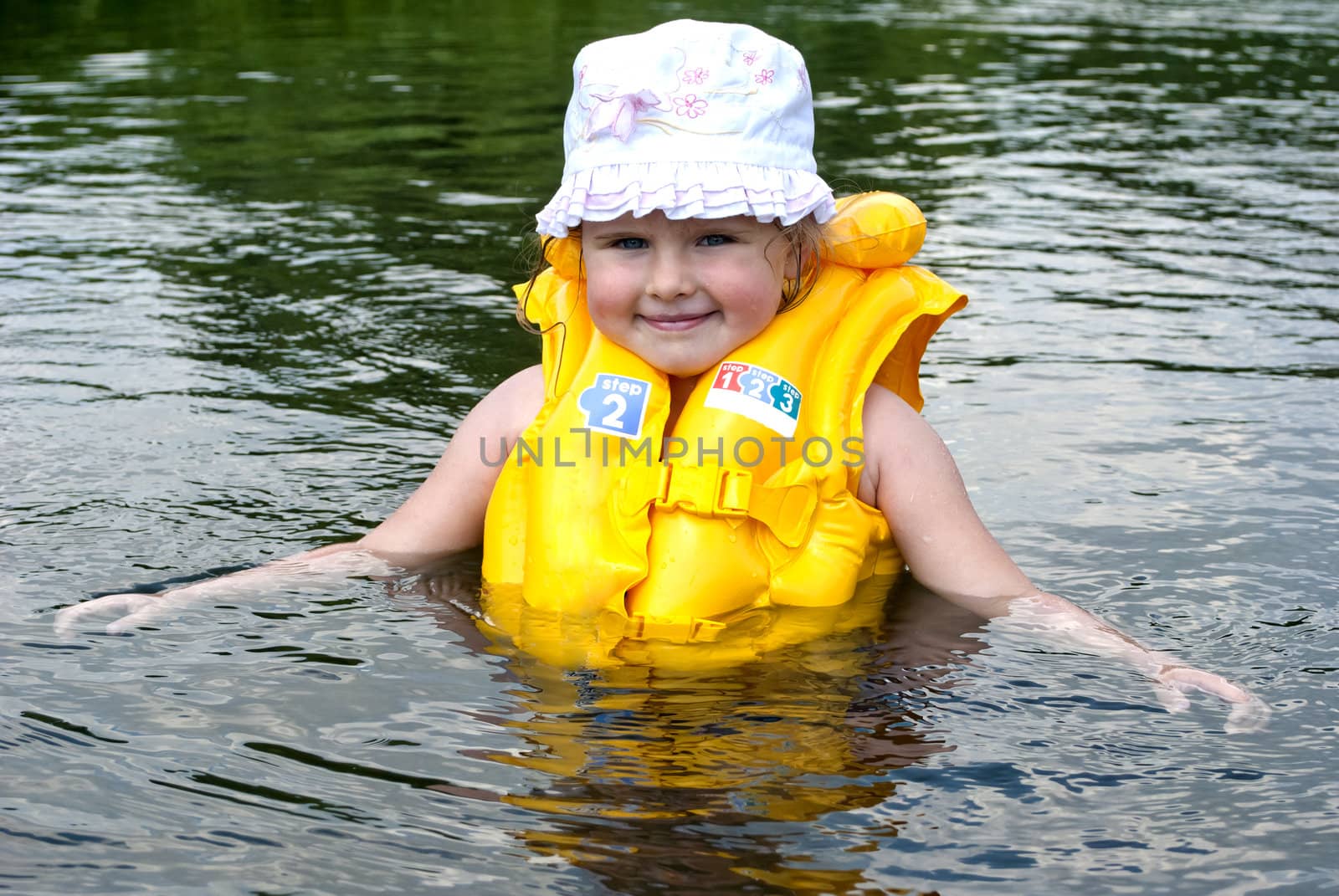 The child dressed in a life jacket studies to float