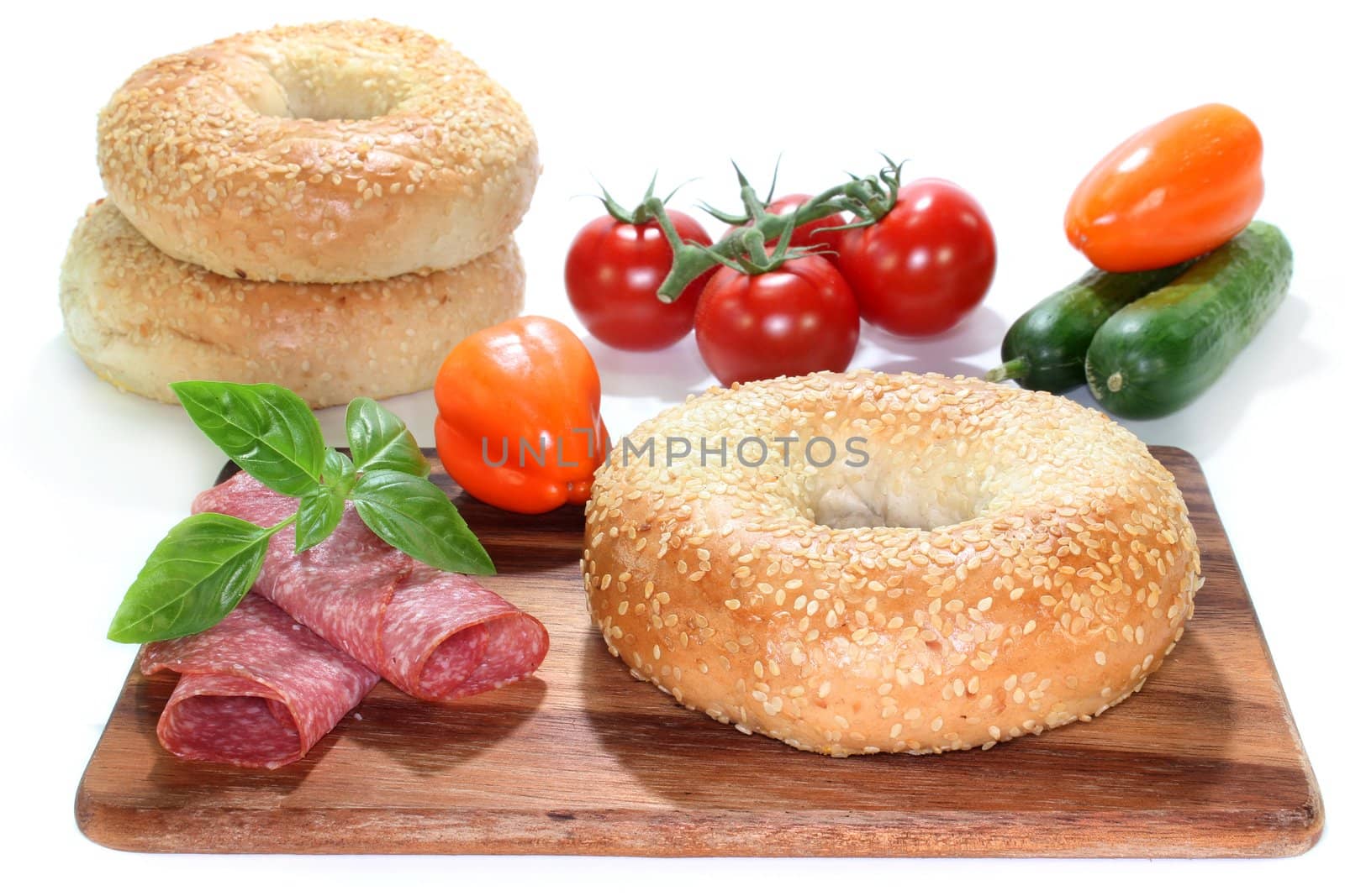 a bagel with salami, bell peppers and cucumber
