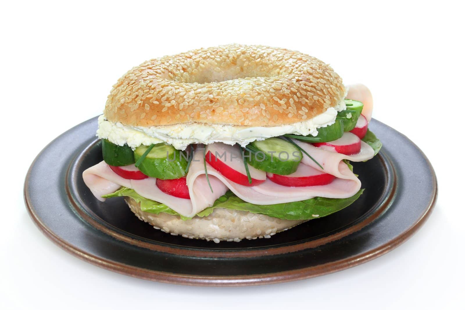 Bagel topped with a breast of turkey, radishes and cucumber
