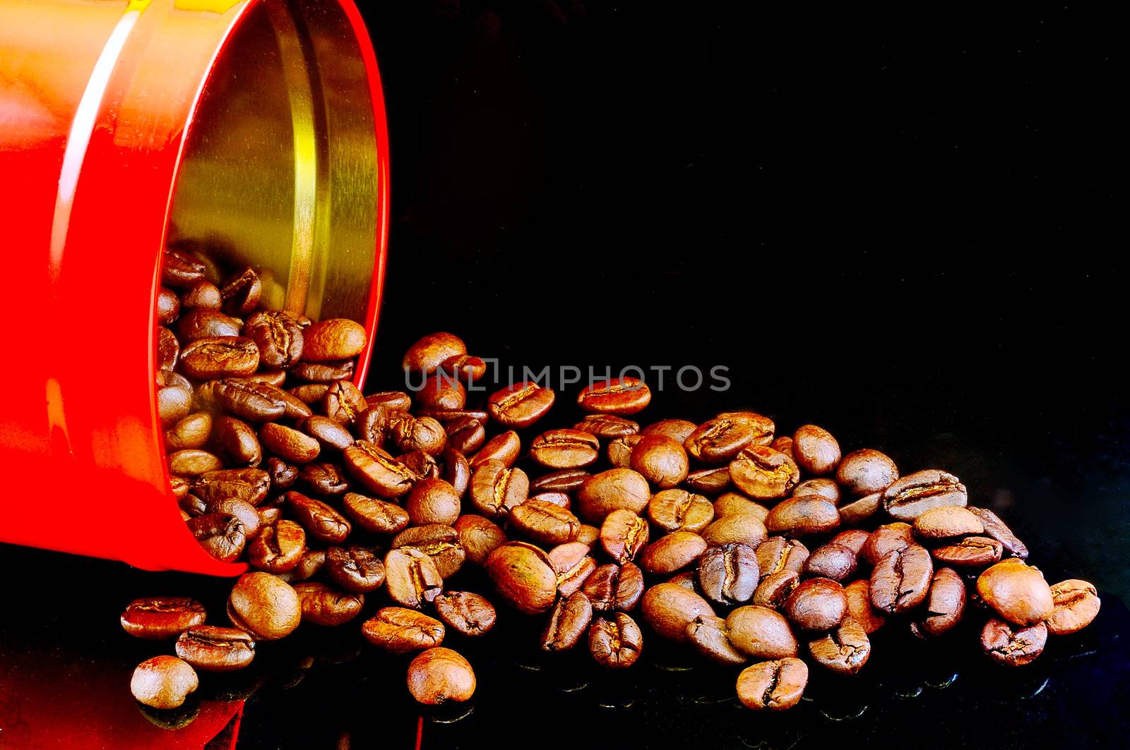 Hot coffee grain poured out of the red picture with the reflection of the banks against a black background