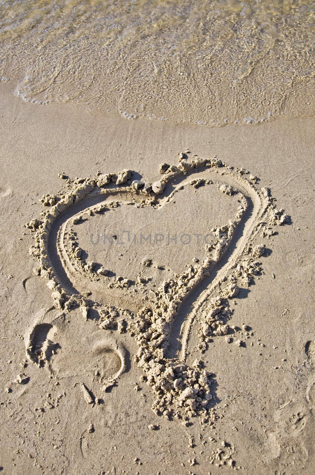 Sign of the heart in the sand. Tidal wave comes to the beach. Concept feeling.