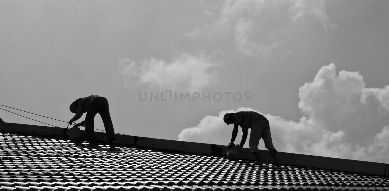Two workmen repair roof in a hot afternoon