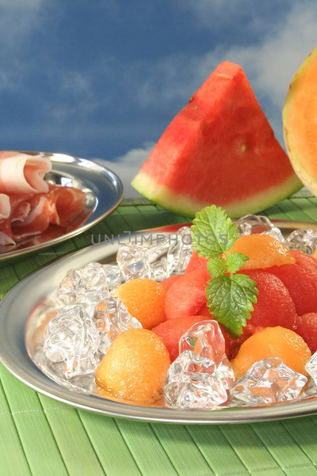 colored melon balls with ham, ice cubes and lemon balm