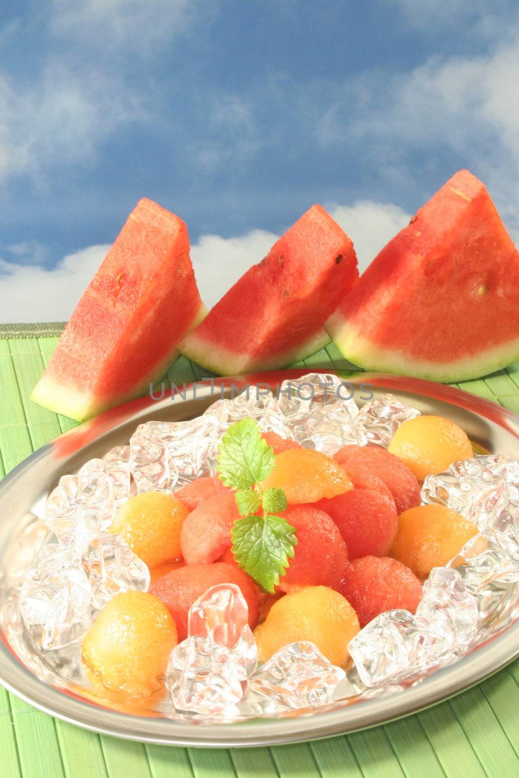 colored melon balls on ice cubes and lemon balm