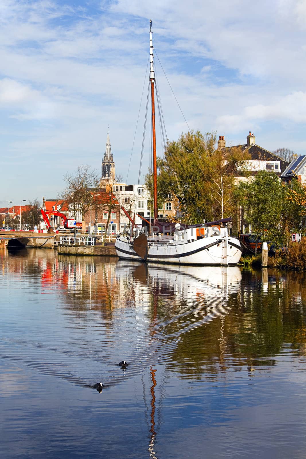 Canal in Delft, the Netherlands, with churchtower, old sailing ship and reflection - vertical