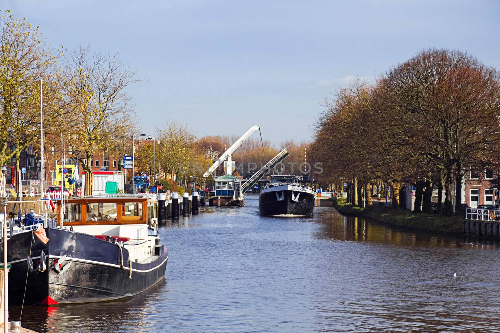Canal with ships and lifting bridge in the Netherlands on sunny day in autumn