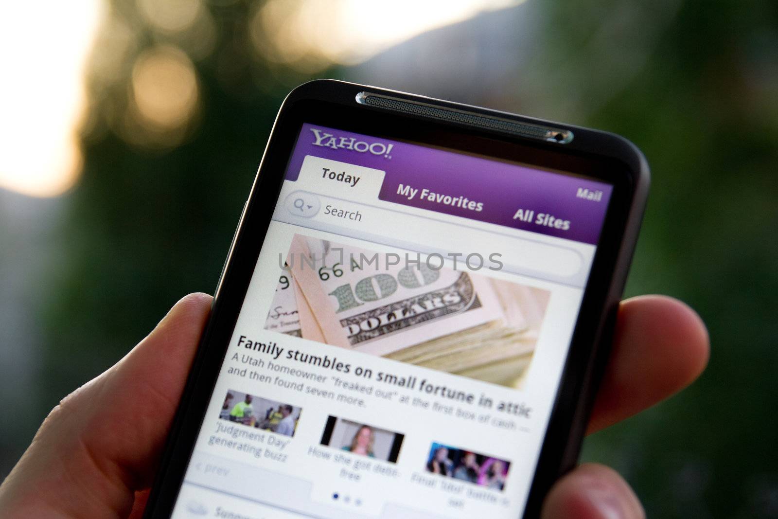 Hand holding HTC Desire HD showing Yahoo news by bloomua