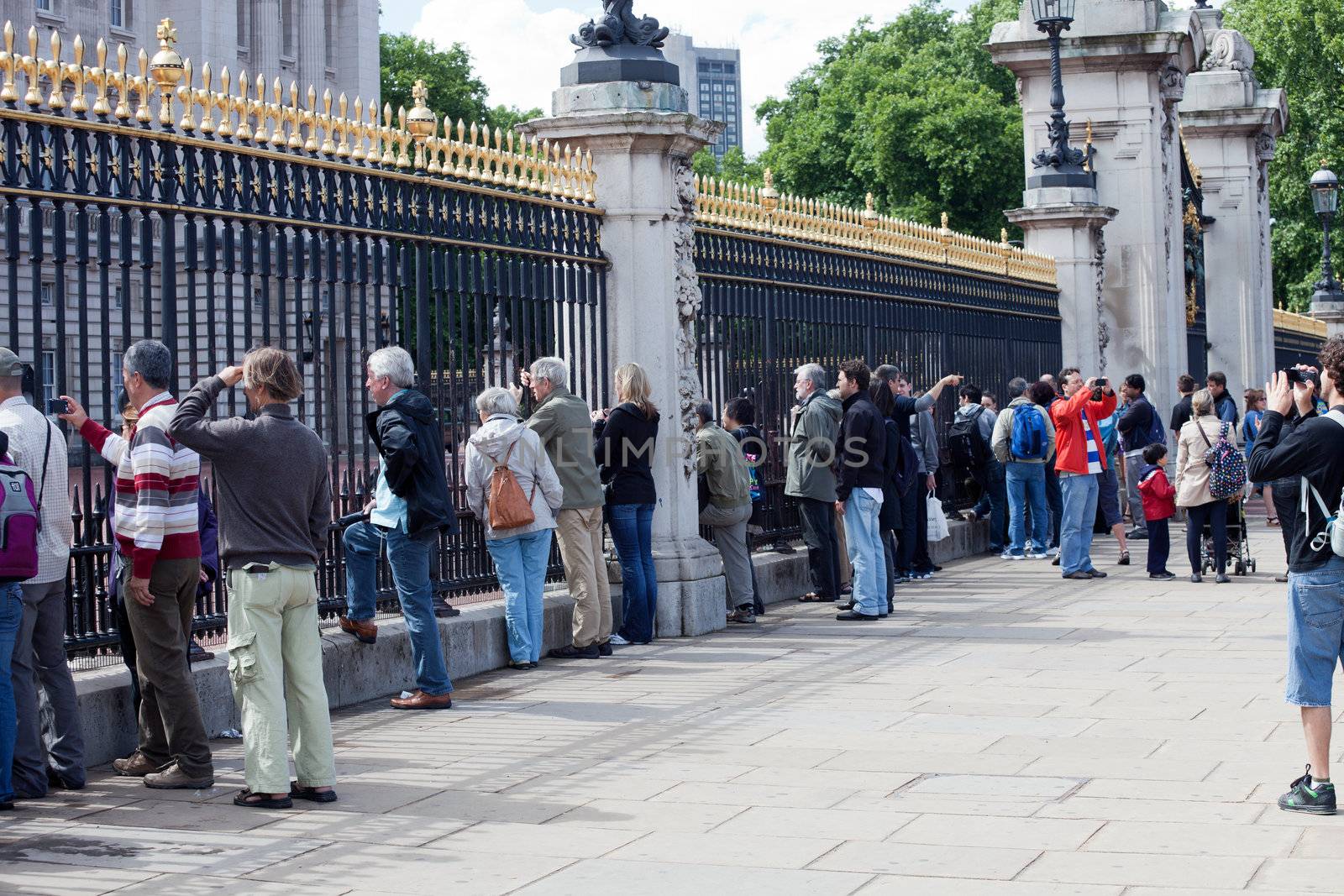 LONDON - JUNE 6: Tourists watch the Royal Guards through fence of the Buckingham Palace on June 6, 2011 in London, UK. Buckingham Palace is the principal residence and office of the British monarch and one of most popular attraction for visitors in London.