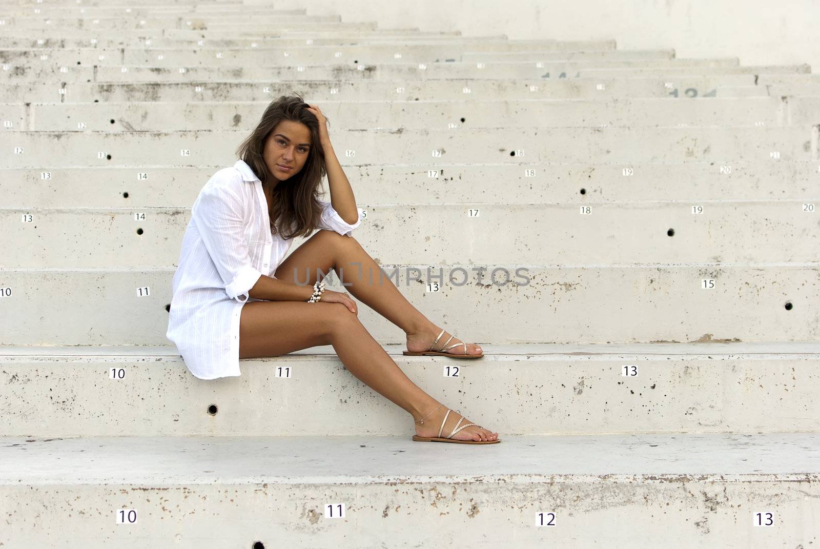Girl in a white shirt sitting in an empty stadium